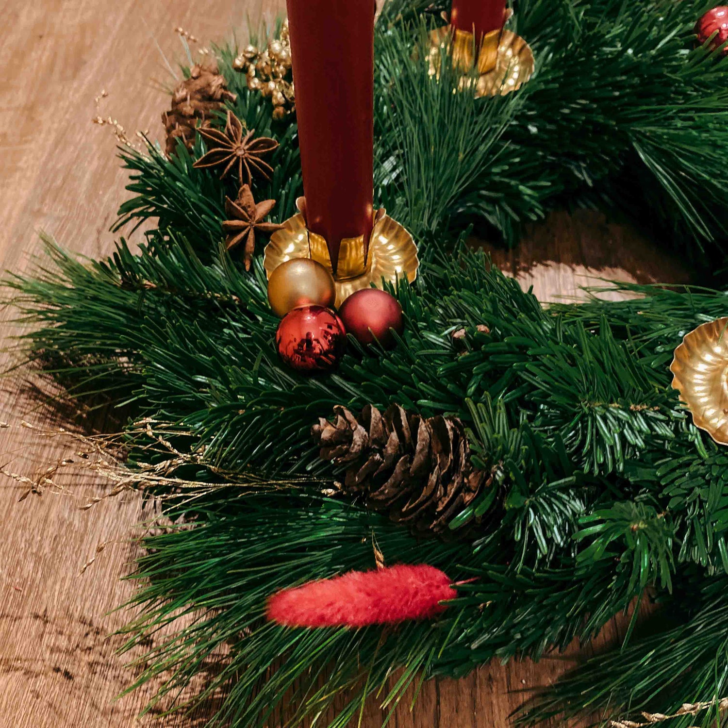 Nahaufnahme von Tannenzweig und roten Kugeln – Adventskranz Rotkäppchen mit Naturmaterialien.