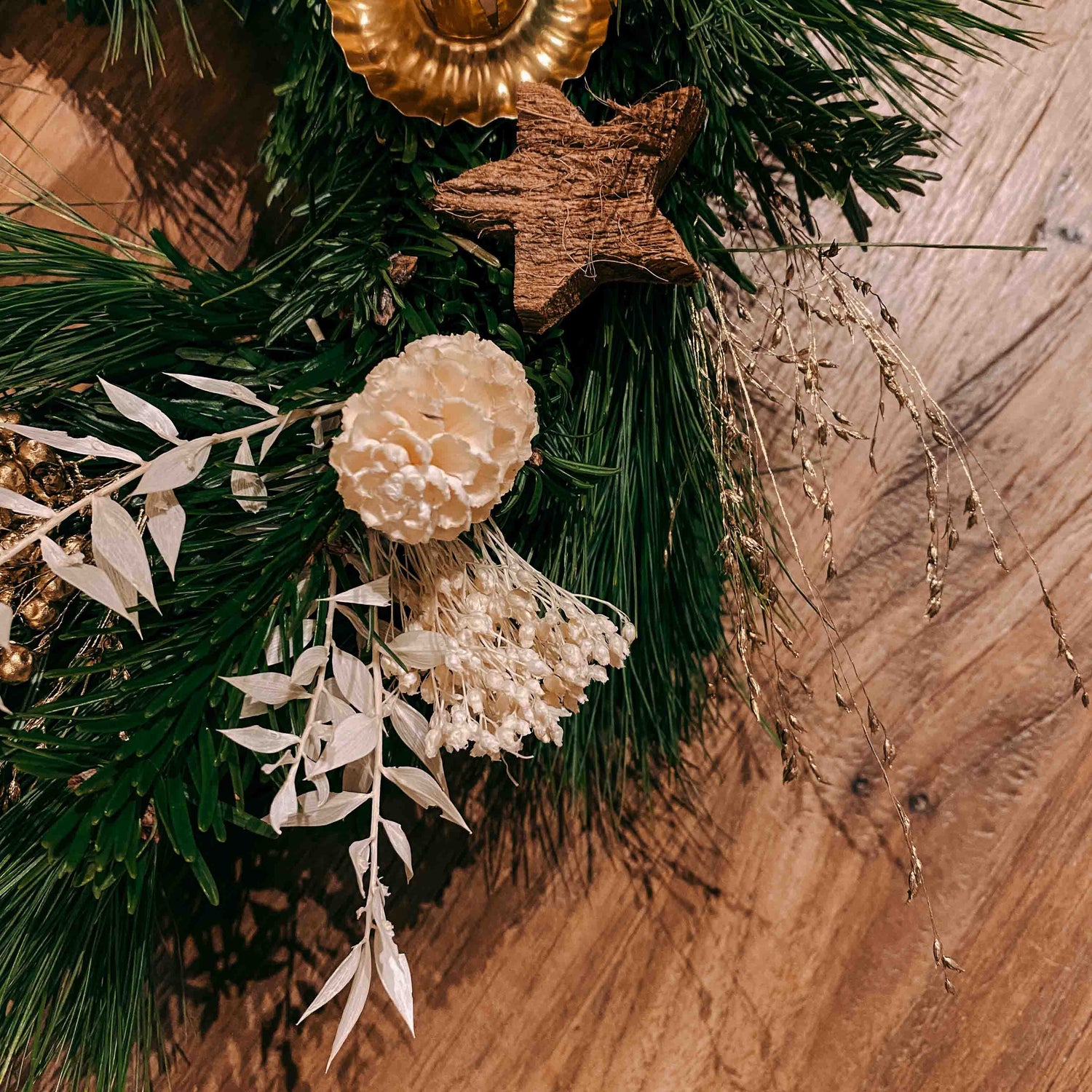 Nahaufnahme: weißer Tannenzapfen und Blätter auf Adventskranz Schneeweißchen mit Goldakzent.