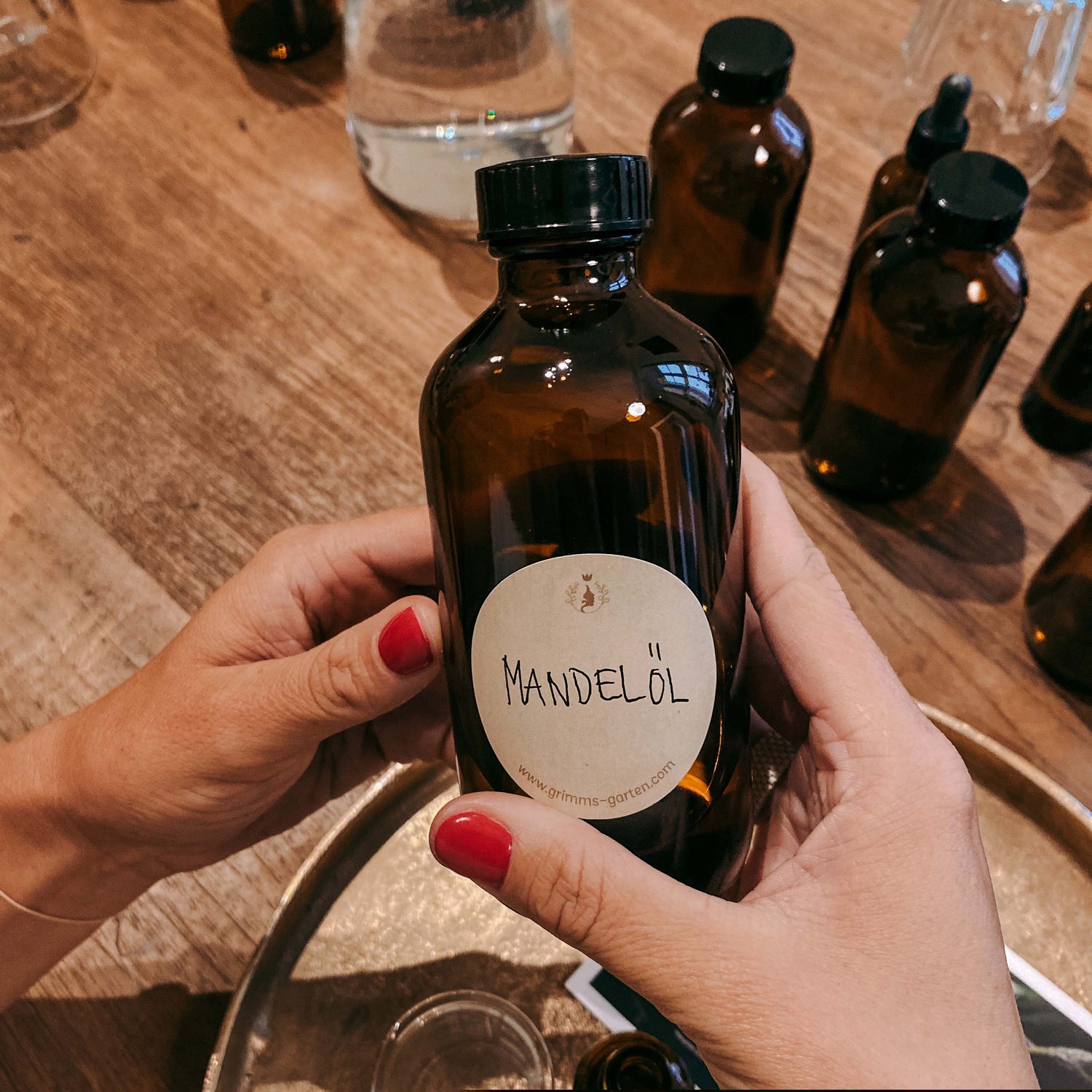 Zwei Hände halten große Flasche mit Etikett „Mandelöl“ – bio kosmetik, hautpflege workshop, diy serum.