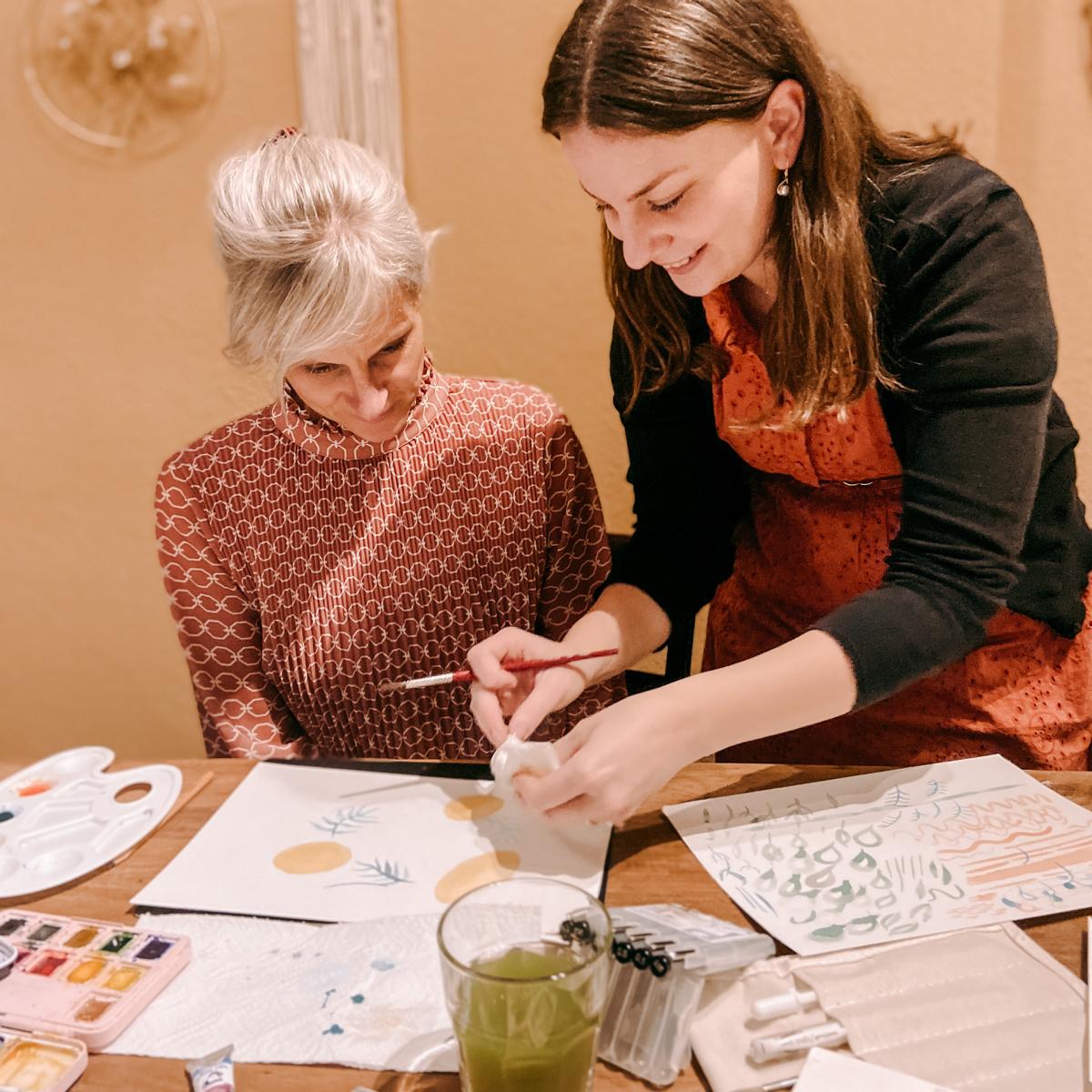 Frau zeigt einer anderen Frau, wie man Blätter malt – Aquarell, Watercolour, DIY Workshop, auch für Firmenevents.