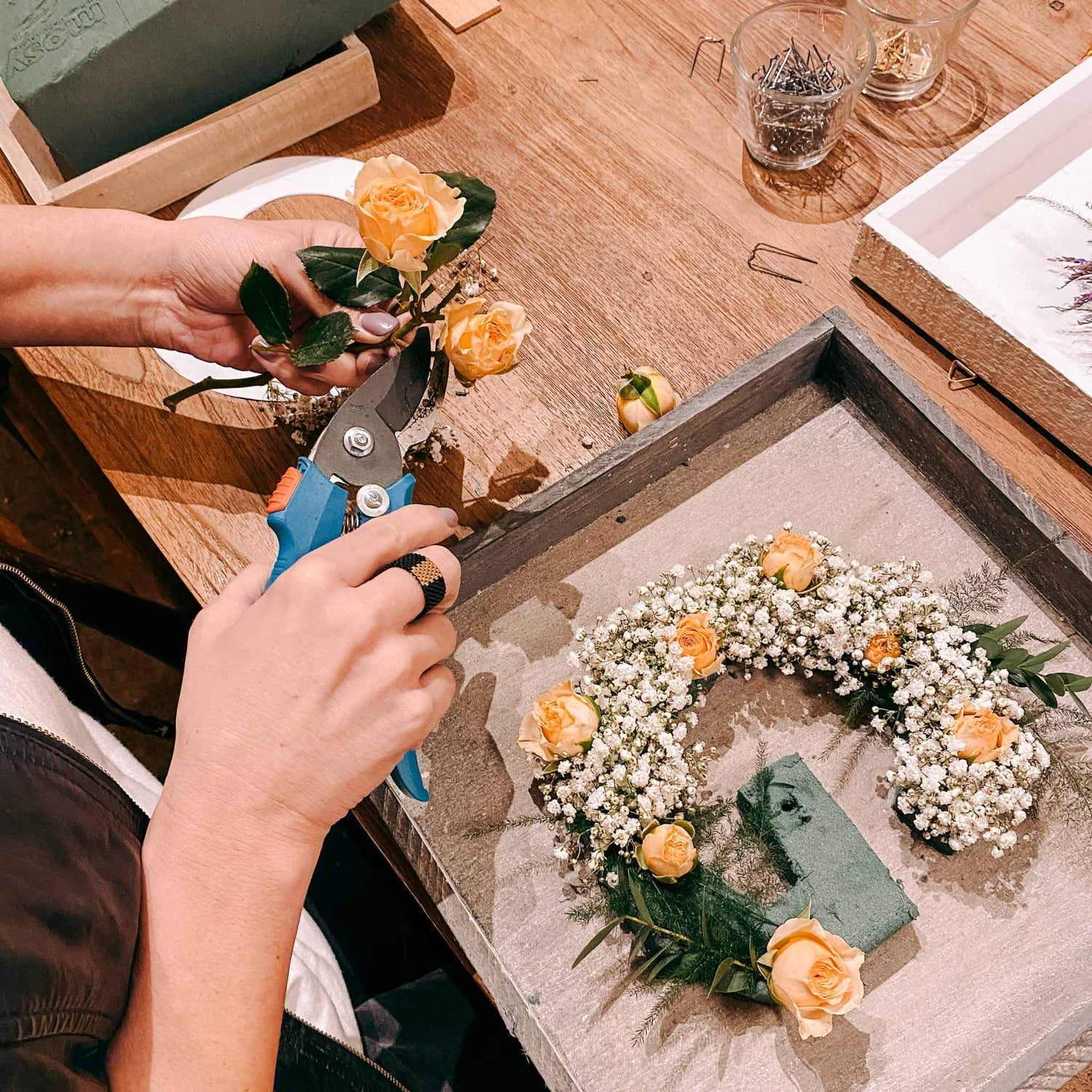 Blumenbuchstabe in Arbeit mit orangenen Rosen und weißen Blüten – trockenblumen deko, diy blumenprojekt.