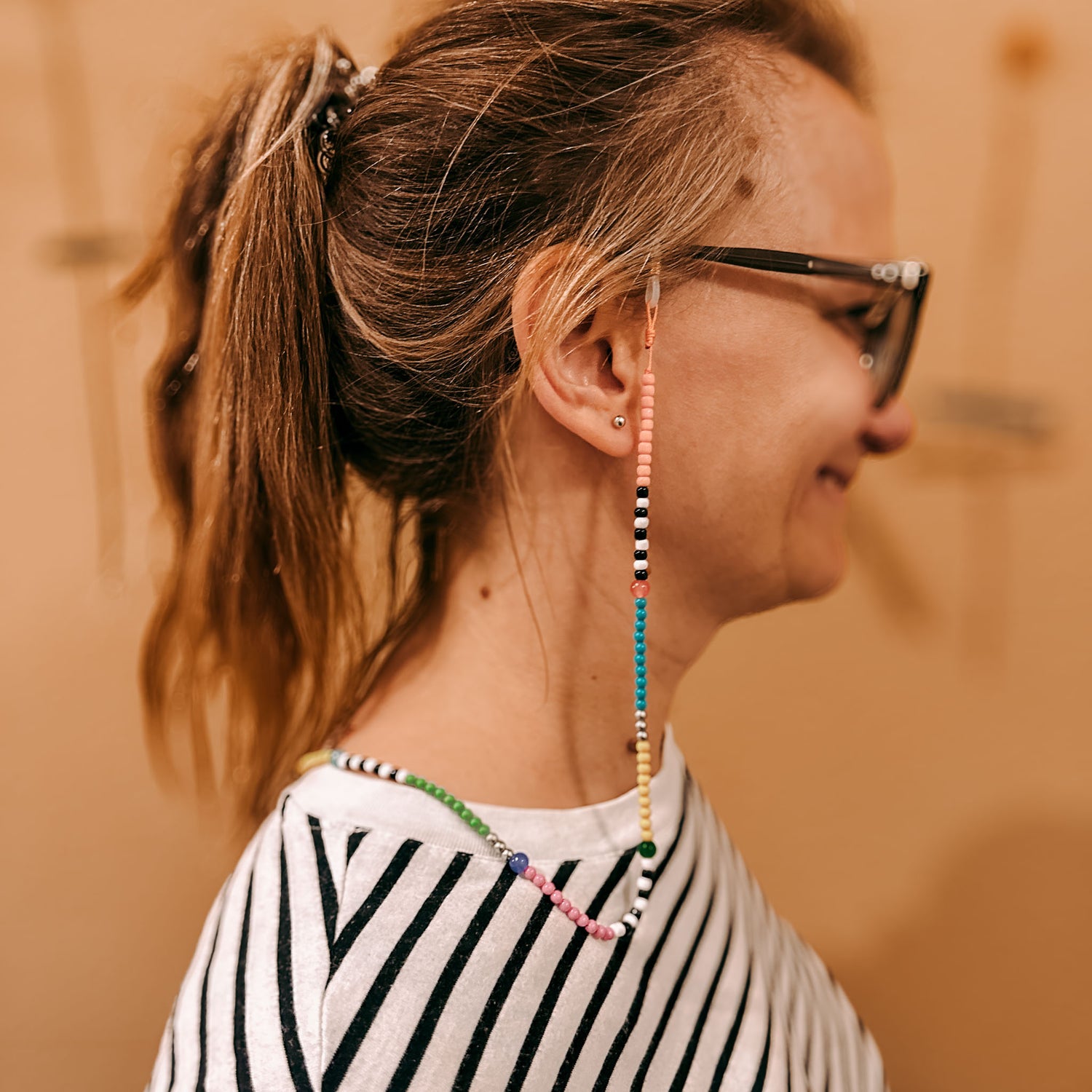 Person trägt Brille mit Perlenband – DIY Perlenschmuck Workshop, Armband kreativ gestalten.