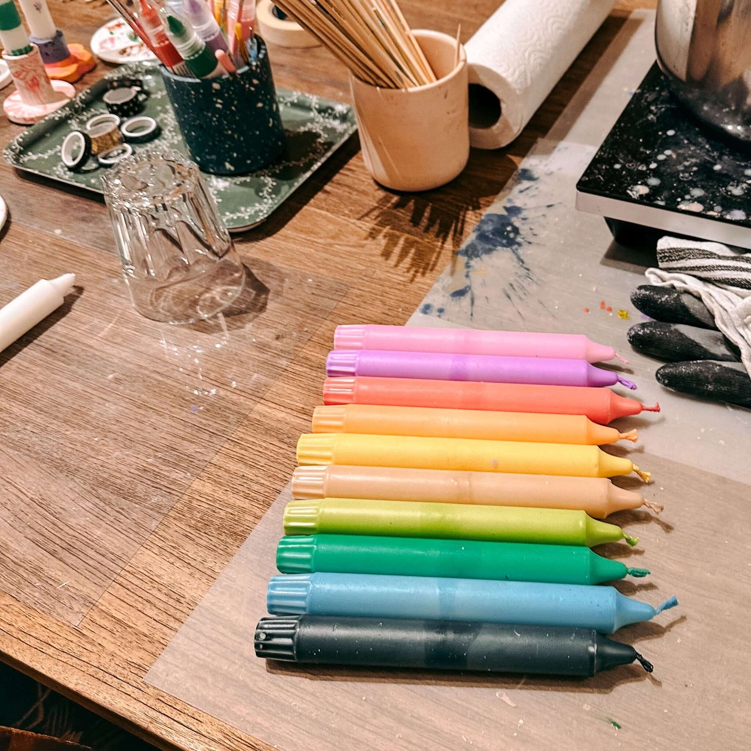 Kerzen in Regenbogenfarben nebeneinander aufgereiht auf Tisch – bunte Kerzen gestalten.