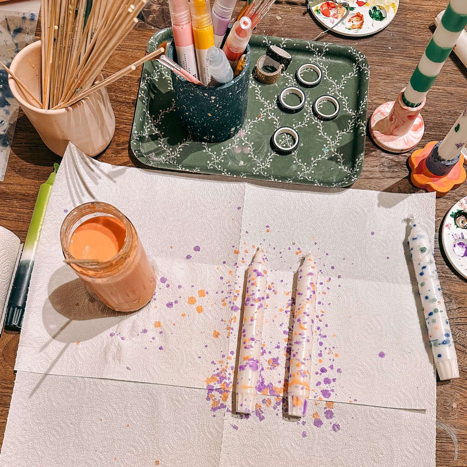 Zwei Konfetti-Kerzen auf Tuch mit Materialien drumherum – DIY Kerzen Workshop Zubehör.