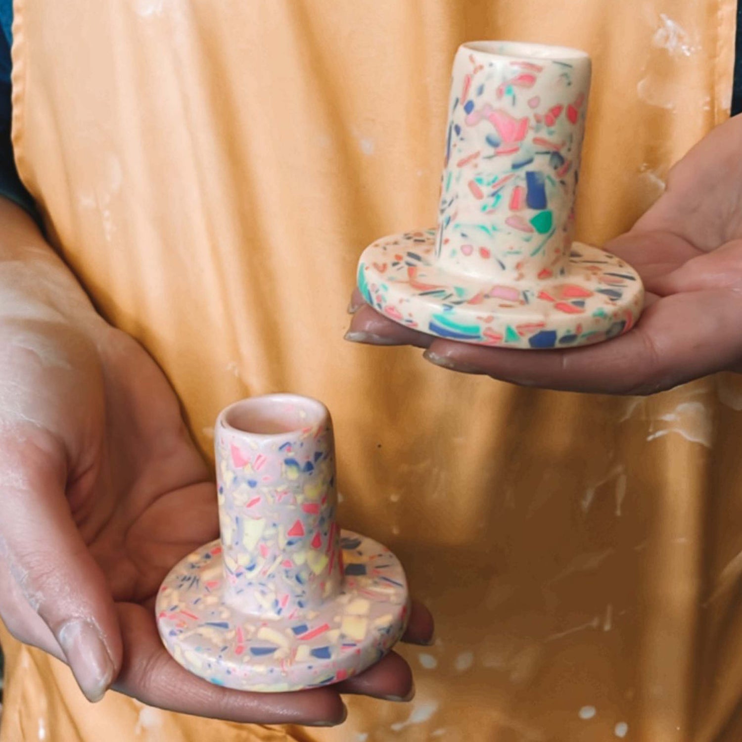 Zwei Hände halten farbige Kerzenständer – DIY Terrazzo Workshop Berlin Wohnaccessoires