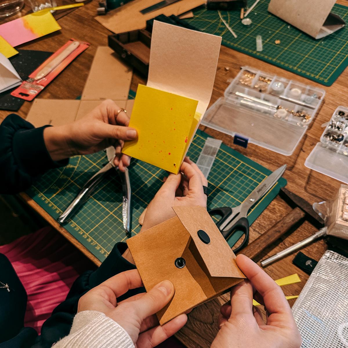 Mehrere Hände halten fertige Portemonnaies mit Schere und Leder – DIY Workshop, nachhaltiges Portemonnaie, Firmenevent.