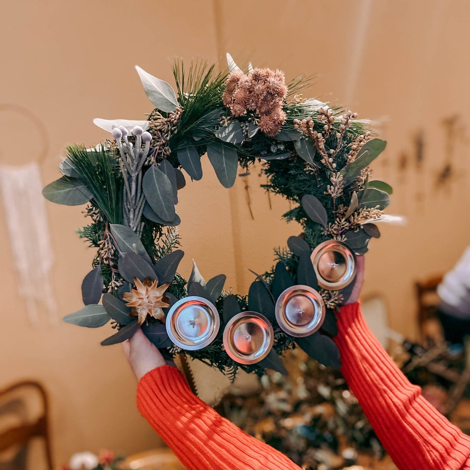 Nahaufnahme eines adventskranz mit Eukalyptus, Trockenblumen und Flächen für Kerzen – weihnachtsgesteck.Auch als Firmenevent buchbar.