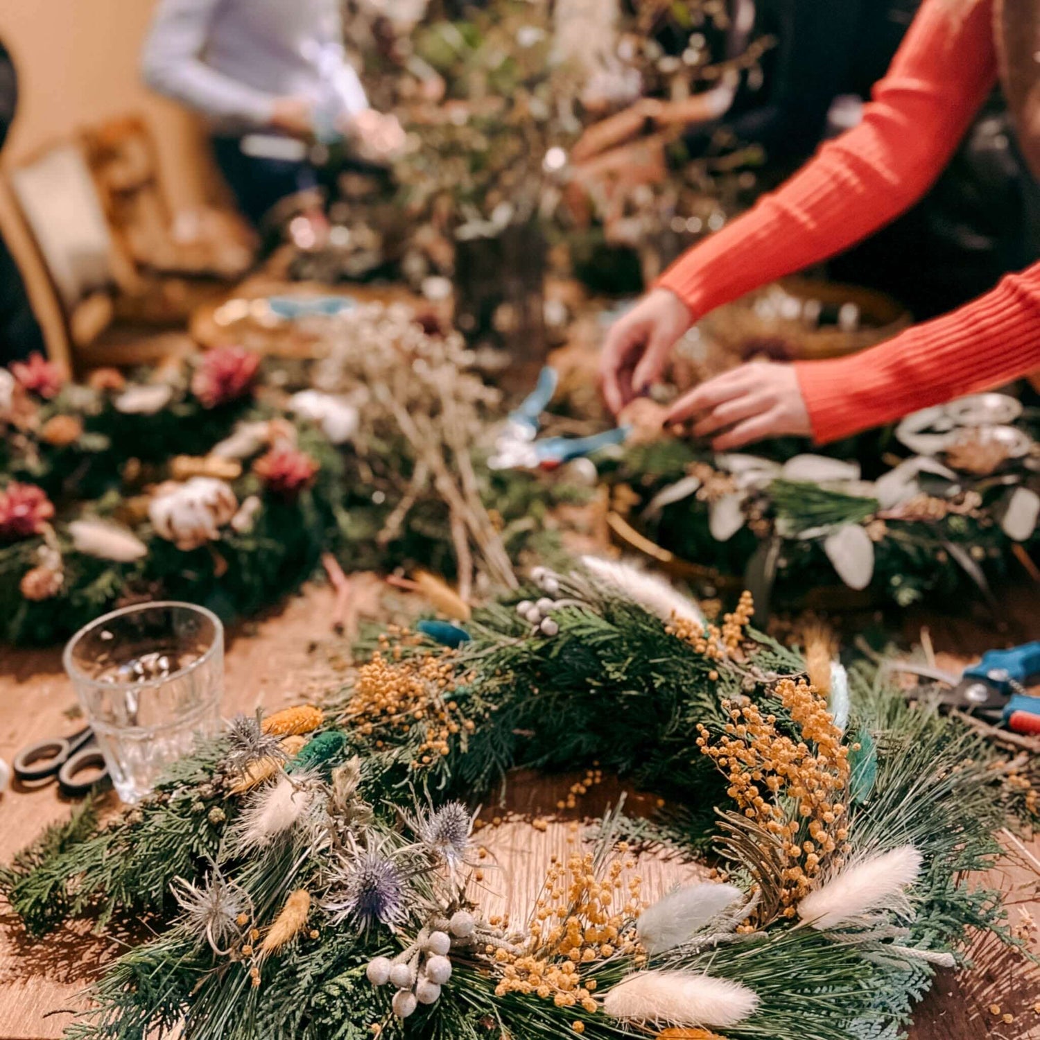 Hand legt Orangenscheibe auf frischen adventskranz – weihnachtskranz selber machen.Auch als Firmenevent buchbar.