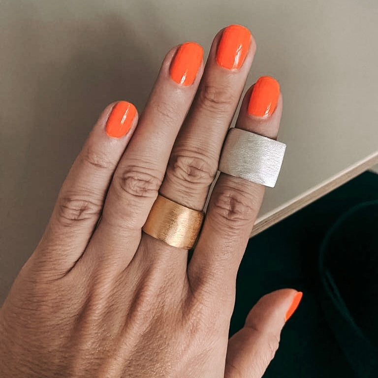 Hand hält einen Gold- und einen Silberring – DIY Ring Workshop, individuelles Schmuckstück, Handgemacht.