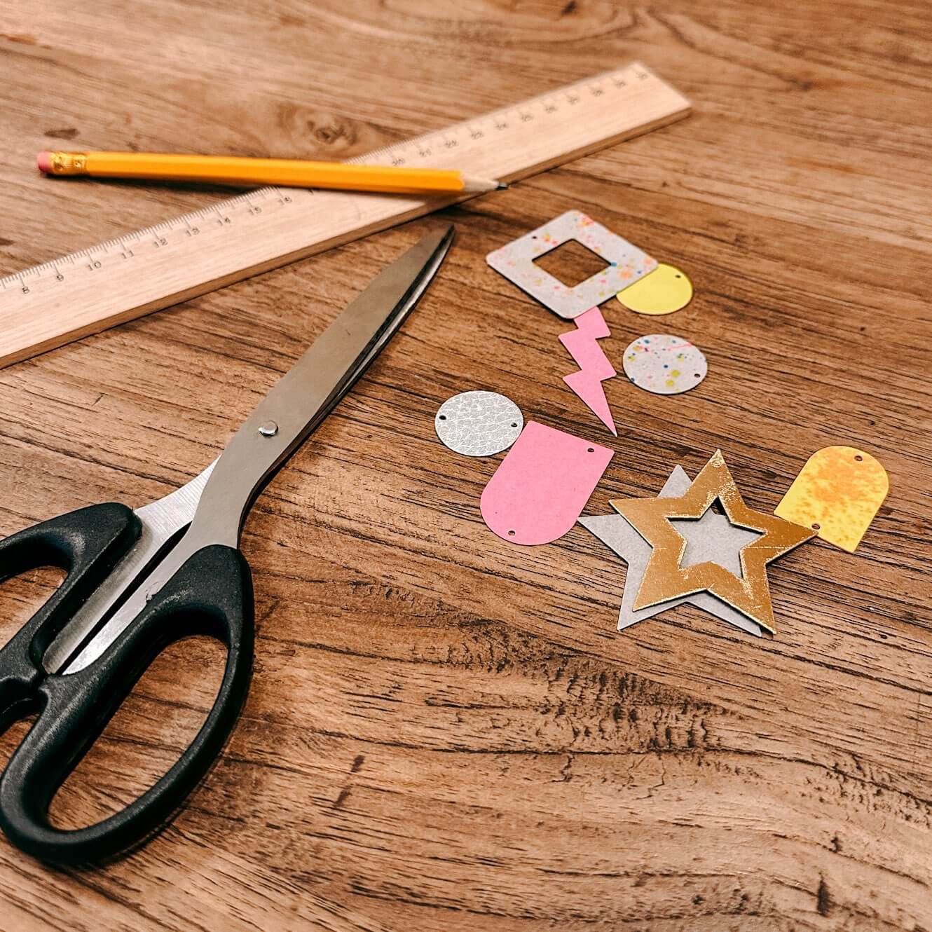 Holztisch mit ausgeschnittenen Ohrringformen, Schere und Lineal – veganes Leder Schmuck Workshop