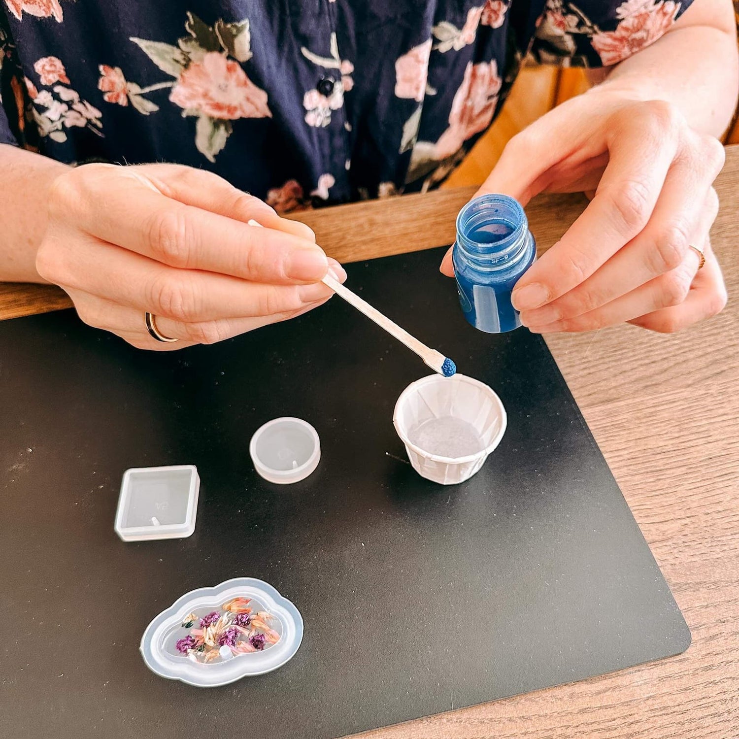 Hände gestalten Resin-Anhänger auf schwarzer Matte – resin schmuck workshop berlin, diy schmuck, auch für Firmenevents.