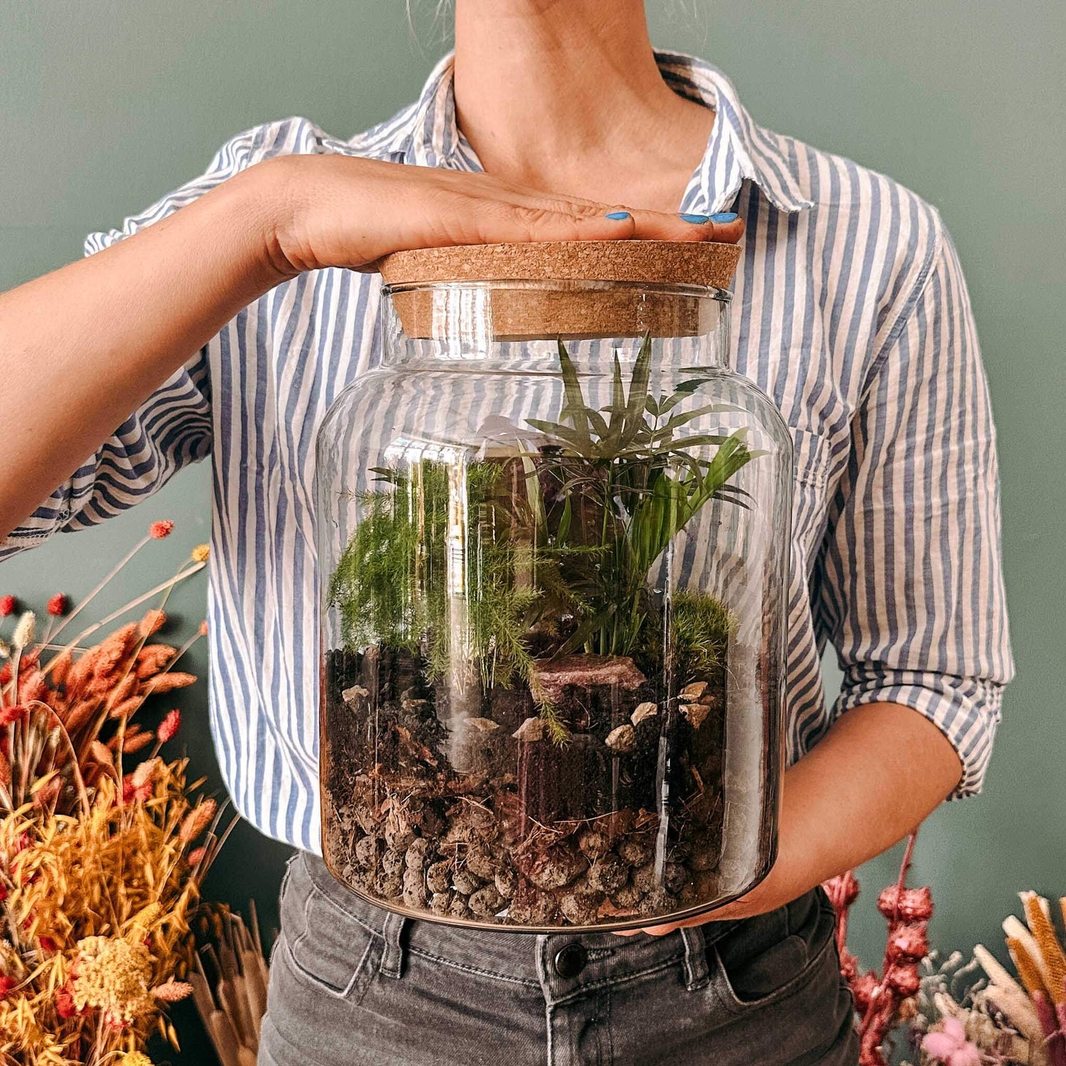 Hände halten selbst gestalteten Flaschengarten – terrarium pflanzen workshop berlin.