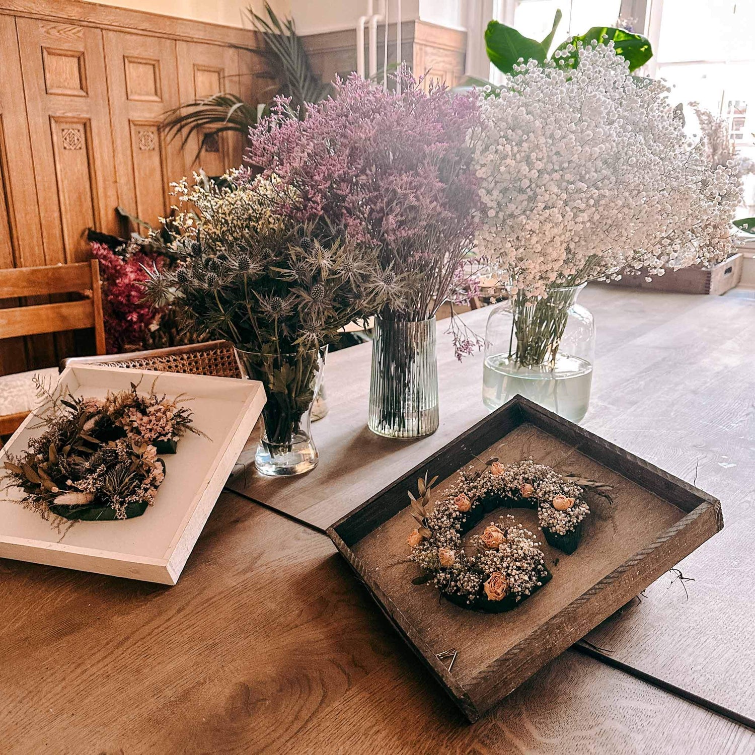 Zwei fertige Blumenbuchstaben auf Holztisch – blumenletter deko, handmade flower monogramm.