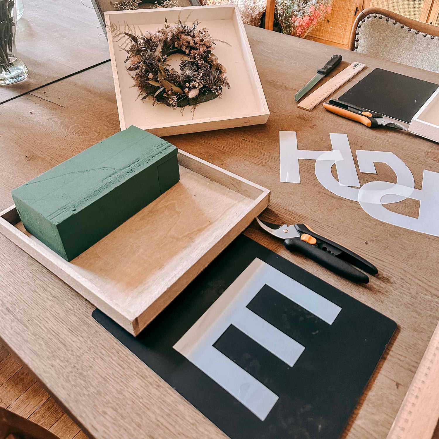 Ausgeschnittenes E mit weiteren Buchstaben auf Tisch – flower monogramm basteln, blumenletter workshop.