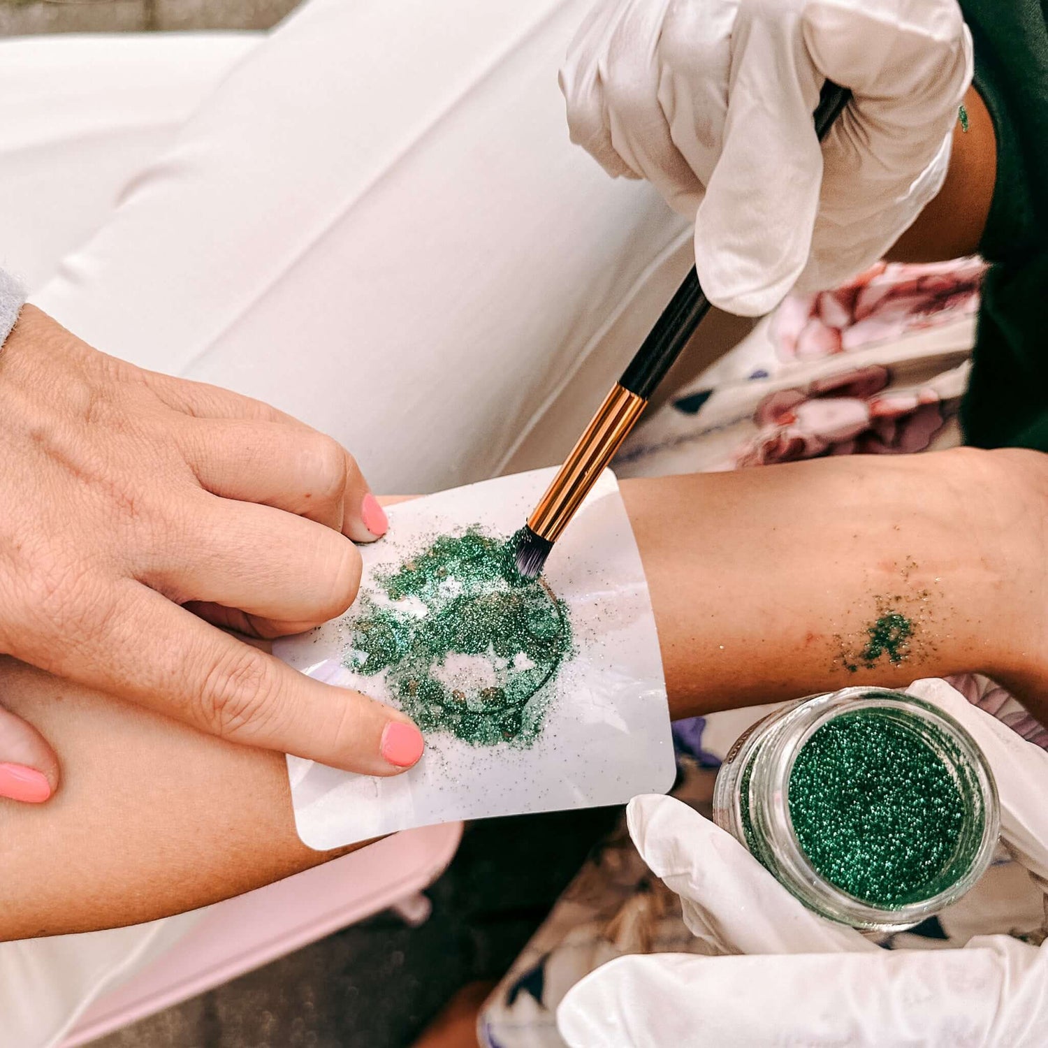 Pinsel trägt Glitzerfarbe mit Schablone auf Arm – kreatives Bio-Glitzertattoo beim Firmenevent.