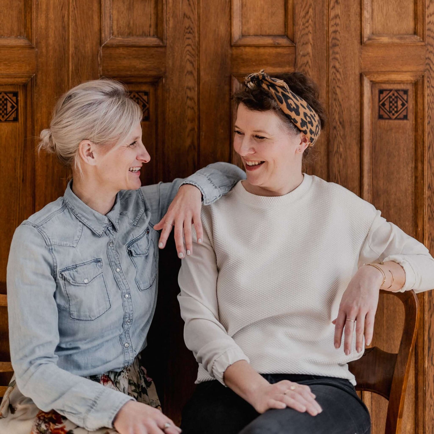 Zwei Frauen sitzen auf Holzbank und lächeln sich an, kreative Workshop-Stimmung bei Grimms Garten Berlin