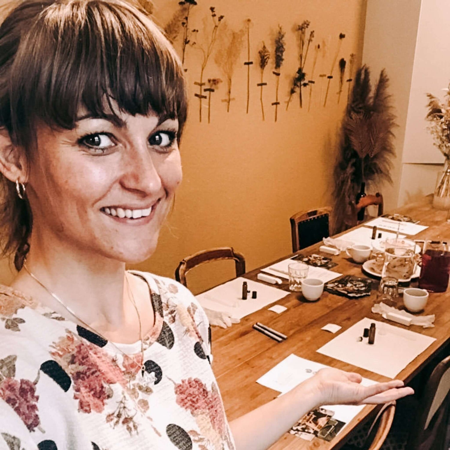 Frau zeigt vorbereitete Arbeitsplätze für kreativen Workshop bei Grimms Garten Berlin