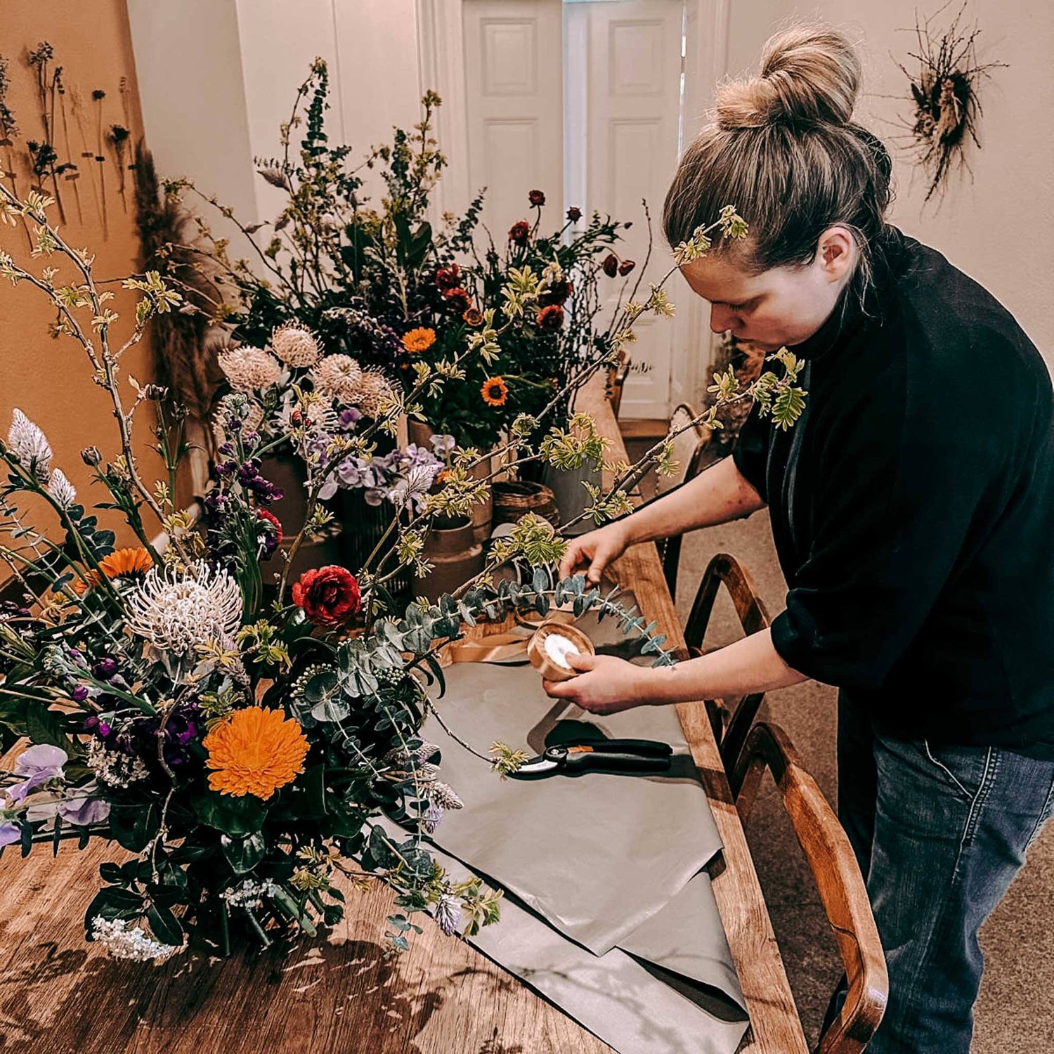Frau bindet Blumensträuße, fertige Sträuße liegen auf dem Tisch, kreativer Workshop bei Grimms Garten Berlin