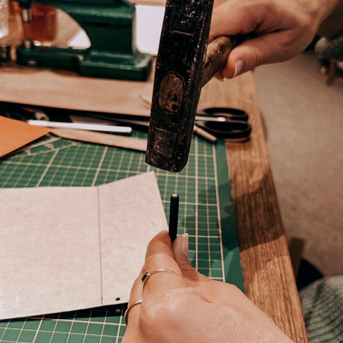 Person stanzt Löcher in veganes Leder mit Hammer und Nagel – DIY Workshop, Leder-Portemonnaie, Firmenevent.