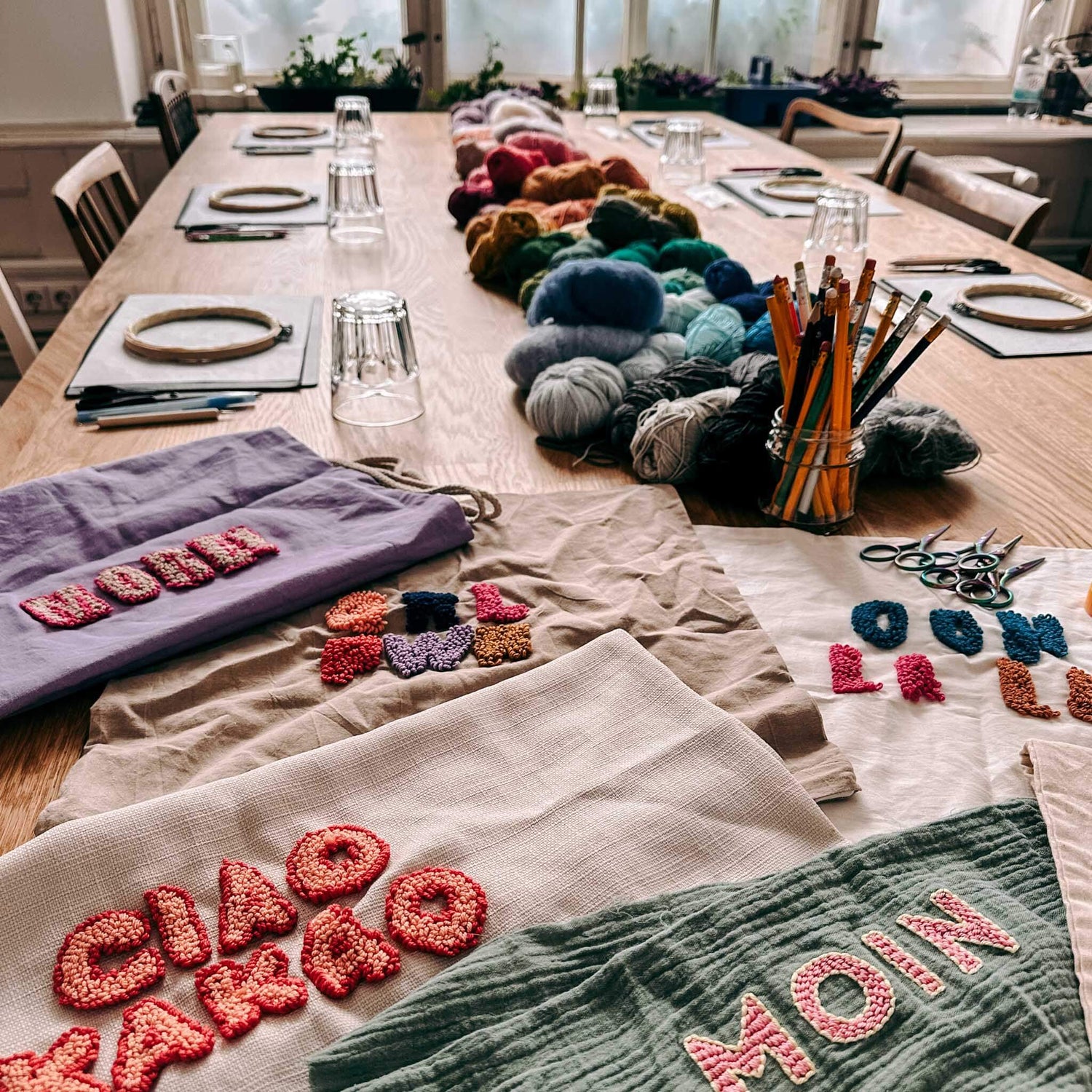 Tisch mit Stoffen, eingepuncht Sprüche und Materialien – kreative textile Kunst Workshop Berlin.