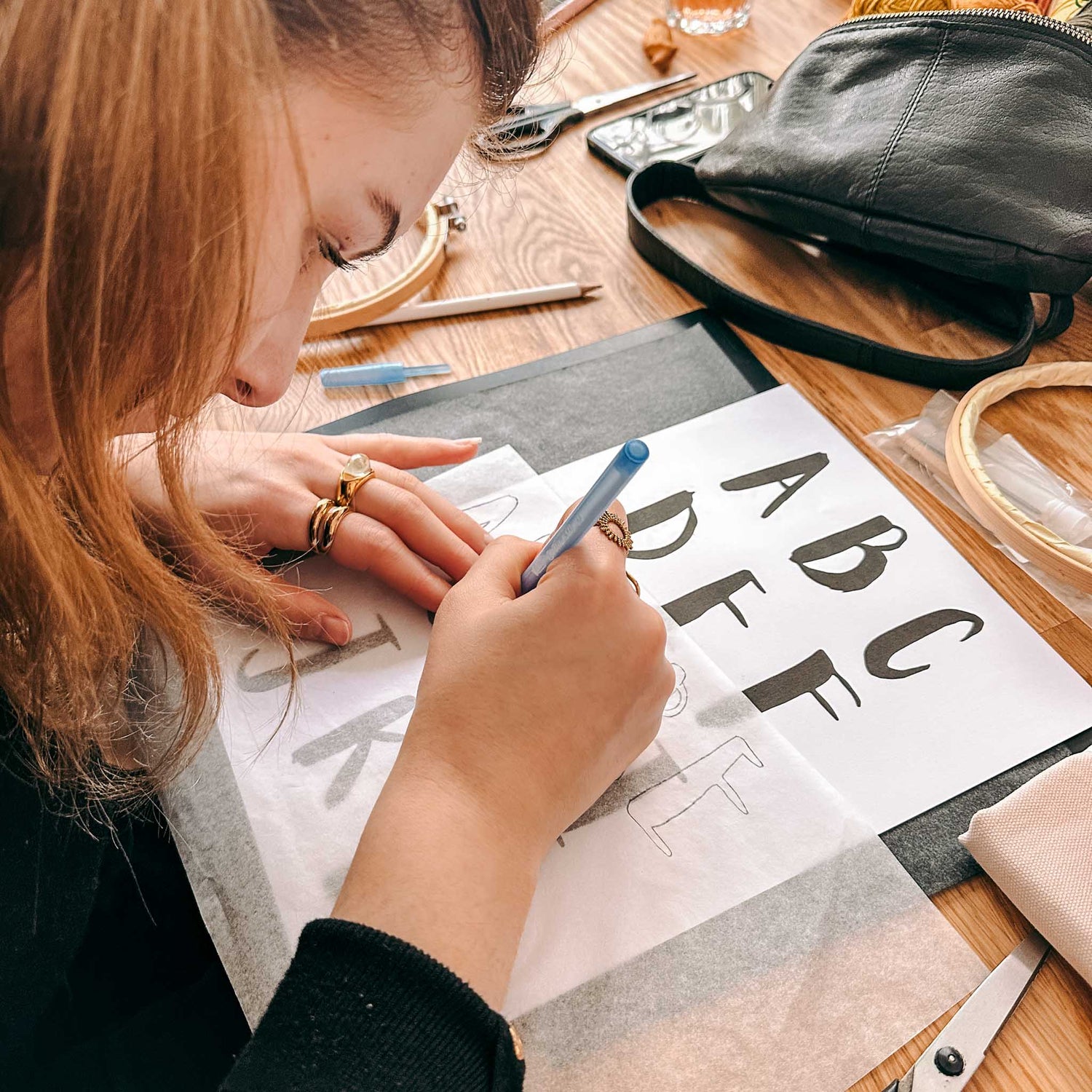 Person überträgt Buchstaben von Zettel auf Stoff – Punch-Needle Workshop, kreative Wohnideen.