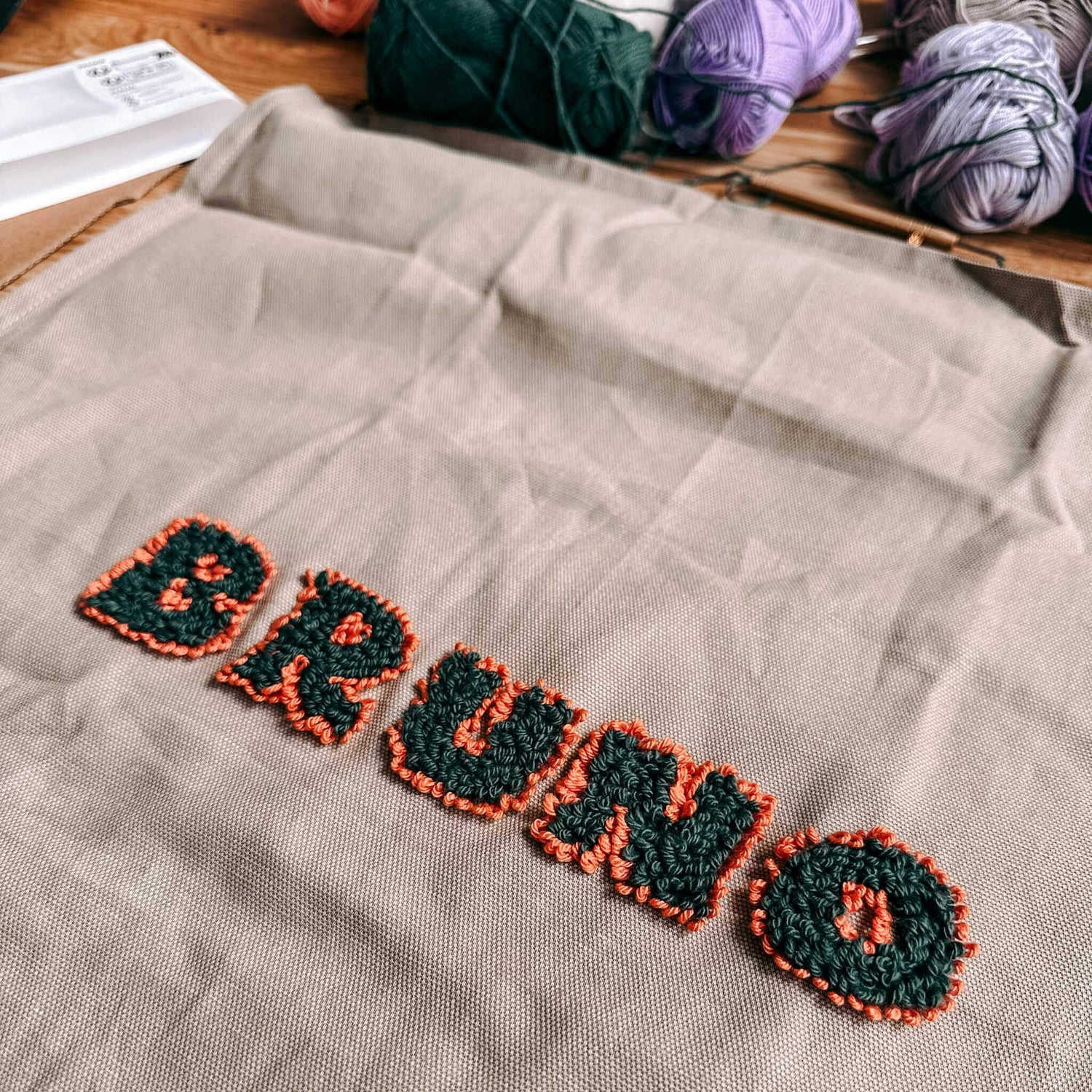 Name „Bruno“ in Grün-Orange auf Stoff mit Wolle – DIY Punch-Needle Kunst Workshop Berlin.