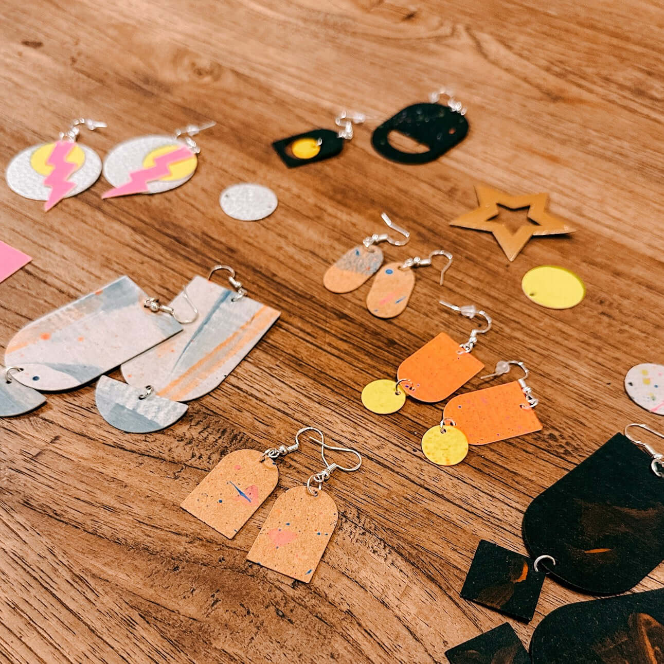 Verschiedene handgemachte Ohrringe aus veganem Leder auf Holztisch – nachhaltiger Schmuckkurs.