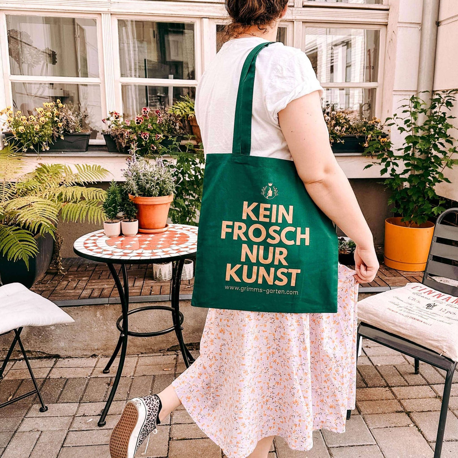 Person trägt nachhaltigen Jutebeutel „KEIN FROSCH NUR KUNST“ aus Baumwolle von Grimms Garten im Alltag.