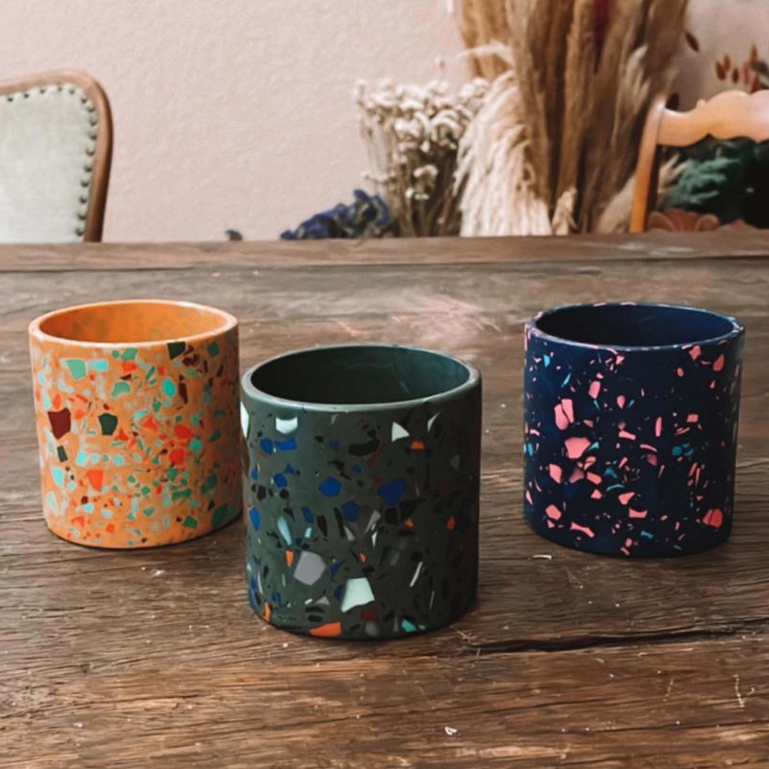 Drei bunte Terrazzo-Pflanztöpfe auf Holztisch – nachhaltiger Terrazzo Workshop Berlin.