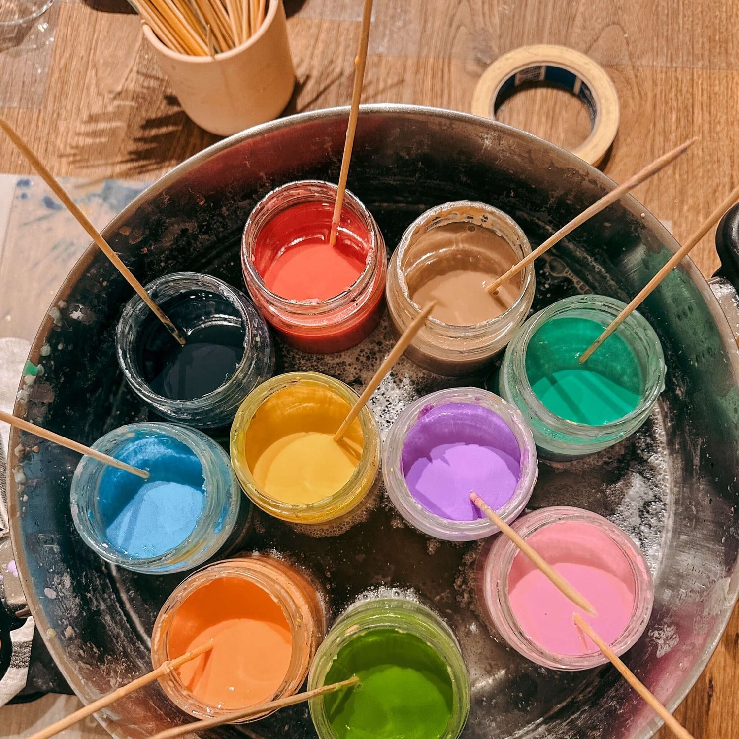 Viele verschiedene Farben geschmolzenes Wachs auf Tisch – Materialien für Dip-Dye Kerzen.