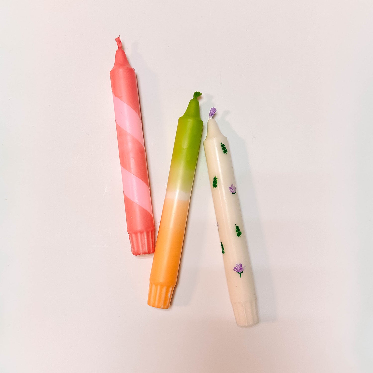 Mehrere bunt gefärbte Kerzen liegen auf Tisch – buntkerzen selber machen, kerzen gestalten.Auch als Firmenevent buchbar.