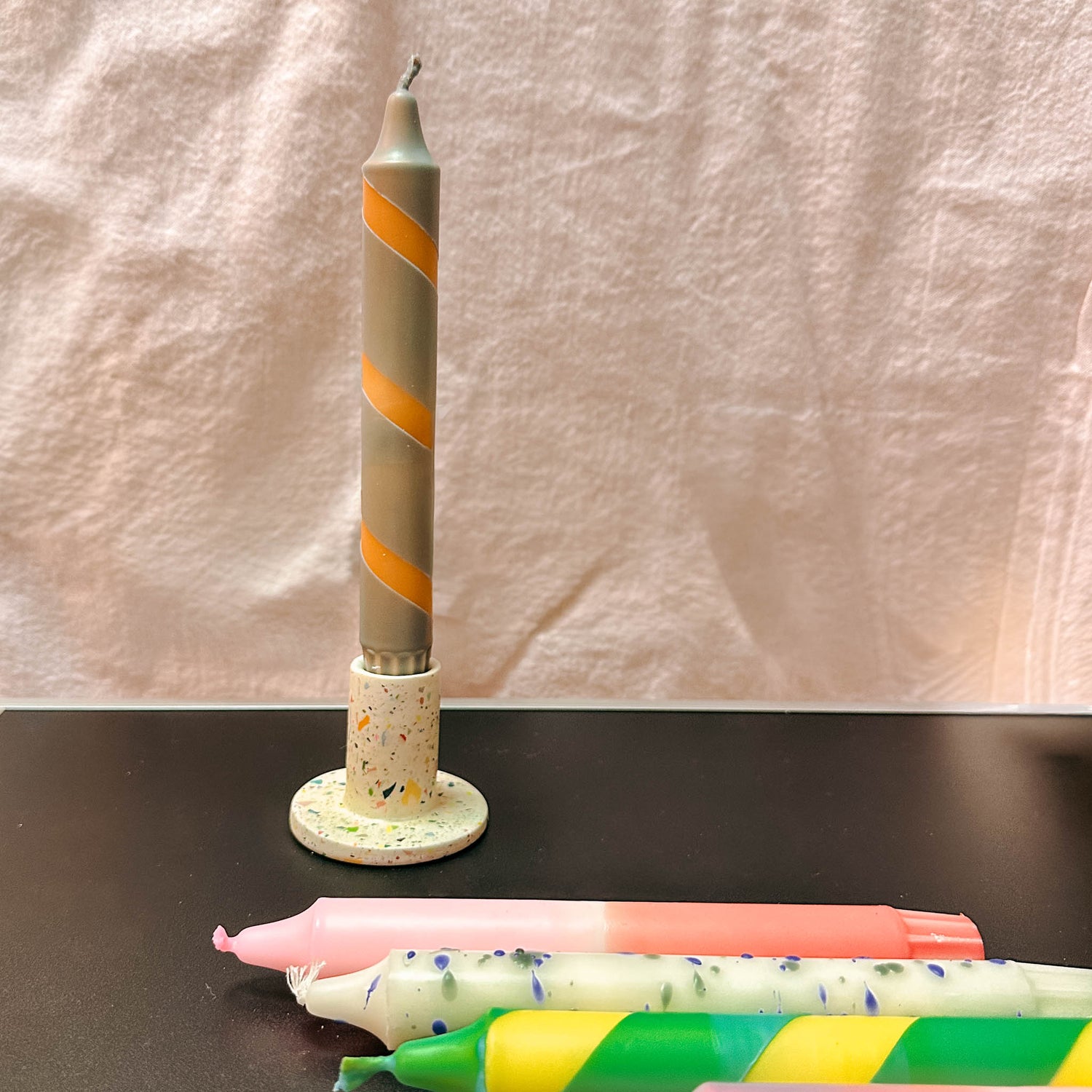 Kerzen mit buntem Farbverlauf und Sprenkeln auf Holzständer – kerzen gestalten, kerzen workshop berlin.Auch als Firmenevent buchbar.