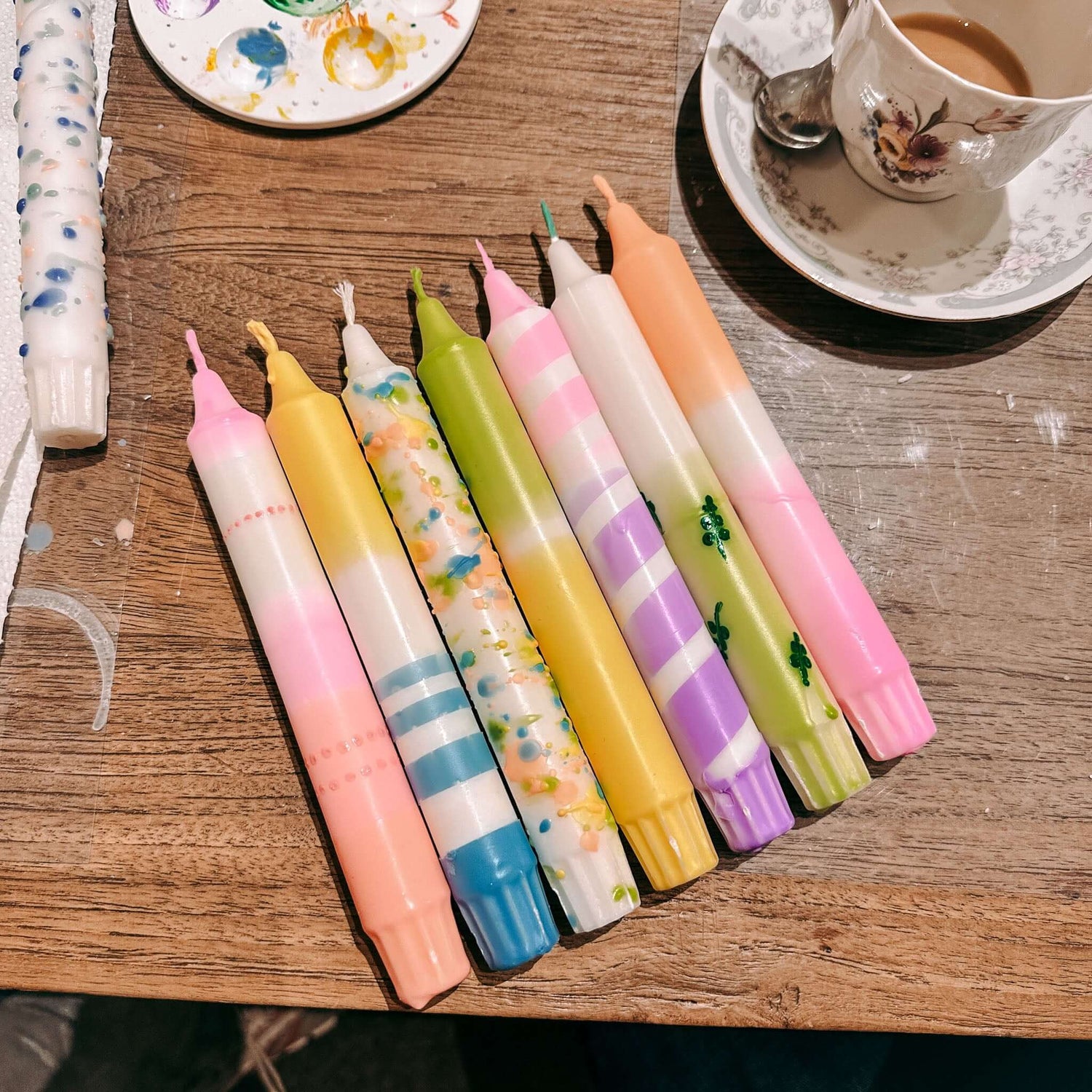 Mehrere Dip-Dye Kerzen in bunten Farben und Mustern auf Tisch – DIY Kerzen Workshop.