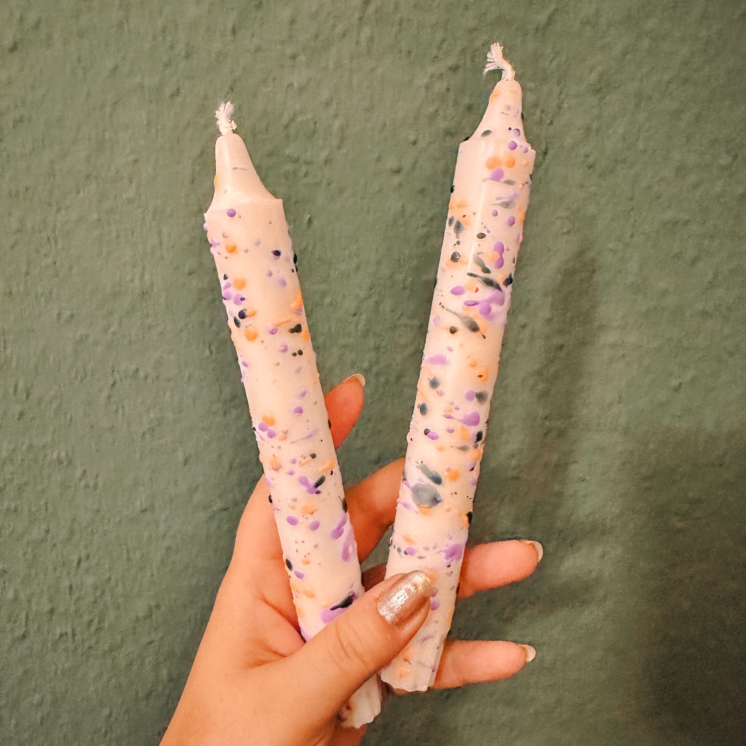 Hand hält eine konfetti Dip-Dye Kerze hoch – kreative Kerzen selber machen.