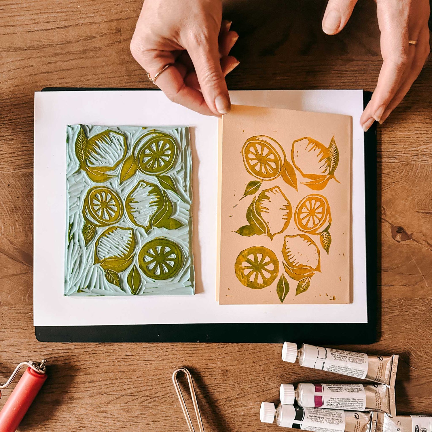 Gelber Zitronendruck auf Blatt, kleine Farbtuben am Rand – Linolschnitt, Linoldruck, DIY Kunstdruck.