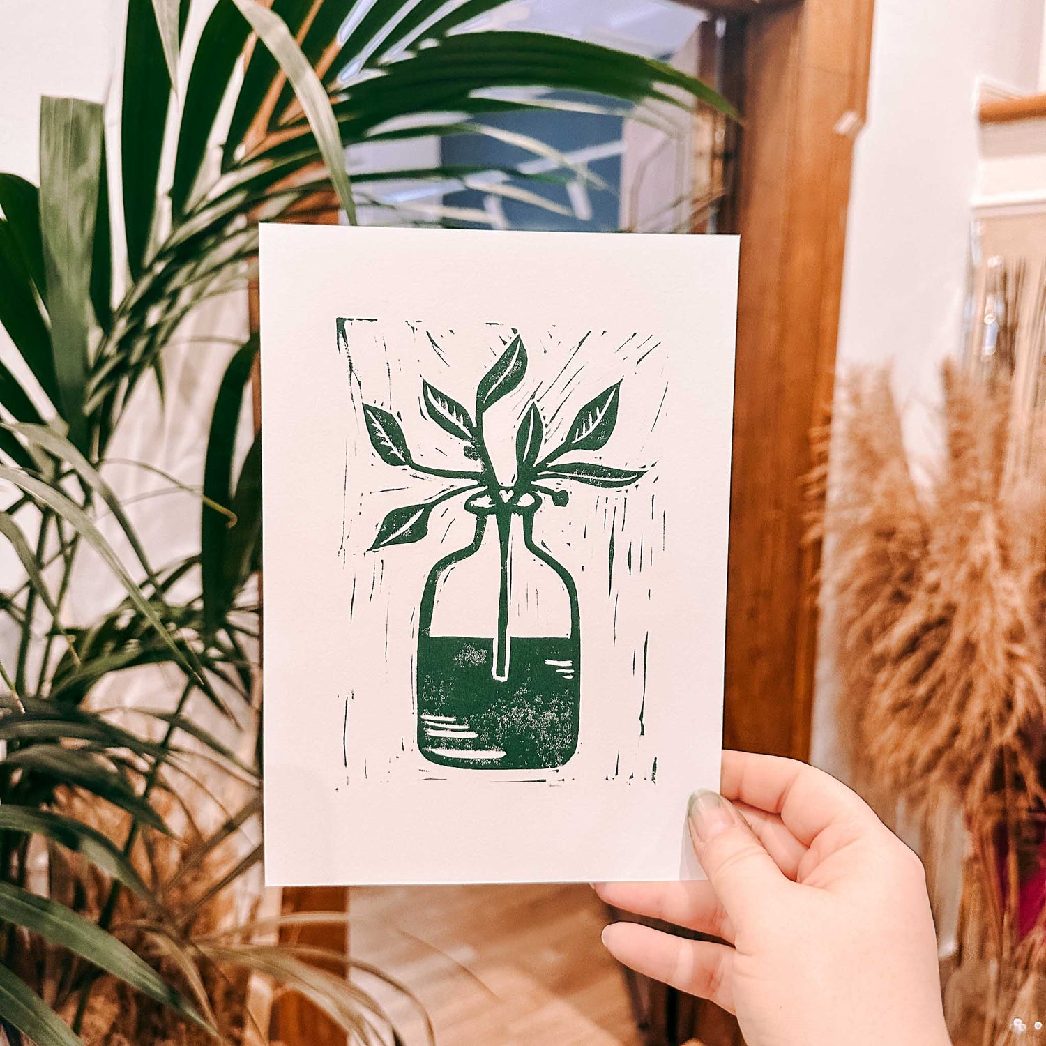 Grüner Pflanzen-Druck auf Karte, Hand hält Karte hoch – Linolschnitt, Linoldruck, DIY Kunstdruck.