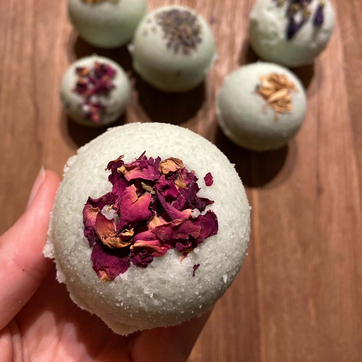 Fertige Badekugeln mit Blüten dekoriert, mehrere im Hintergrund – Badekugel, Badebombe, Entspannung zuhause.