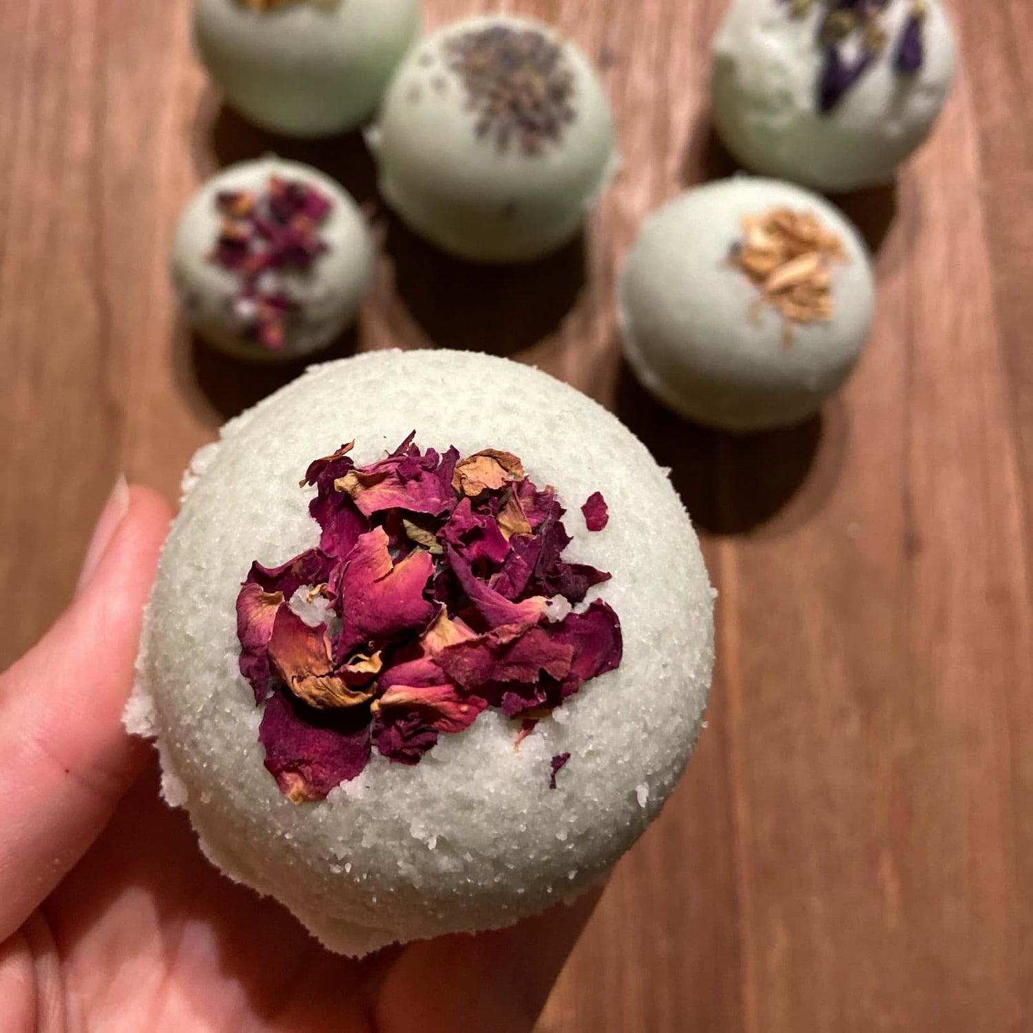 Fertige Badekugeln mit Blüten dekoriert, mehrere im Hintergrund – Badekugel, Badebombe, Entspannung zuhause.