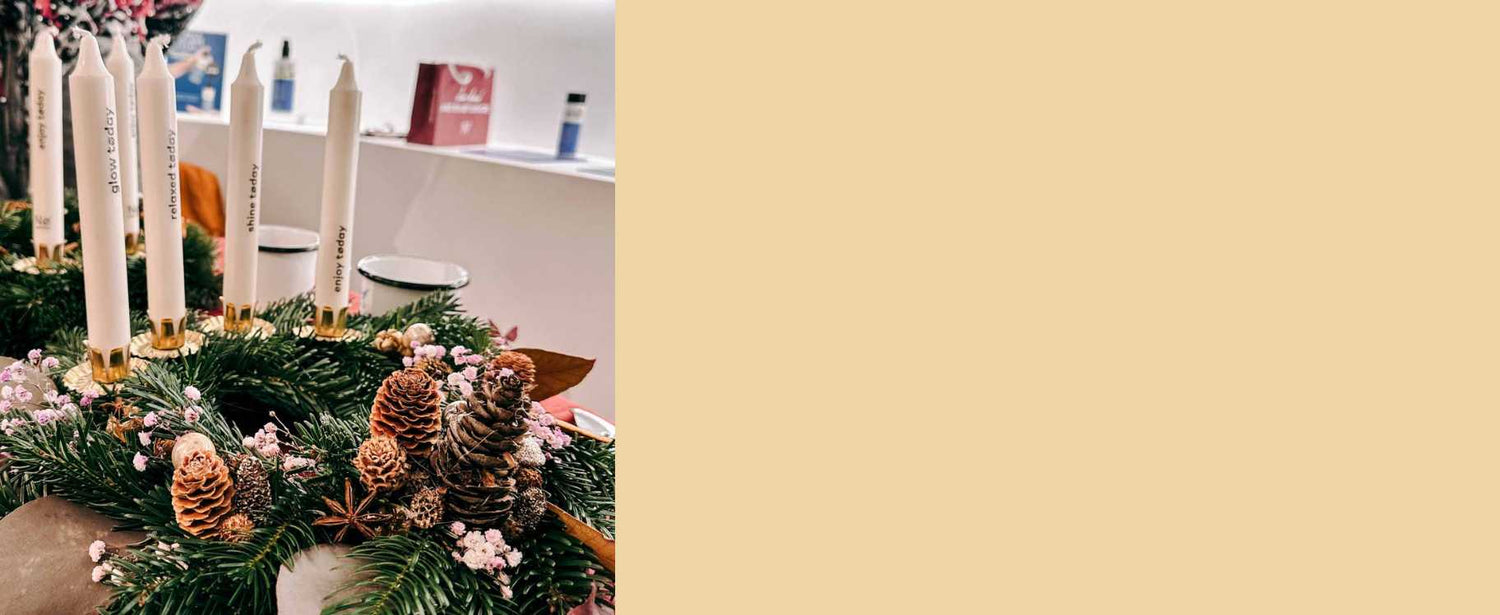 Fertiger Adventskranz mit Tannenzapfen und weißen Kerzen in goldener Fassung auf einem Tisch