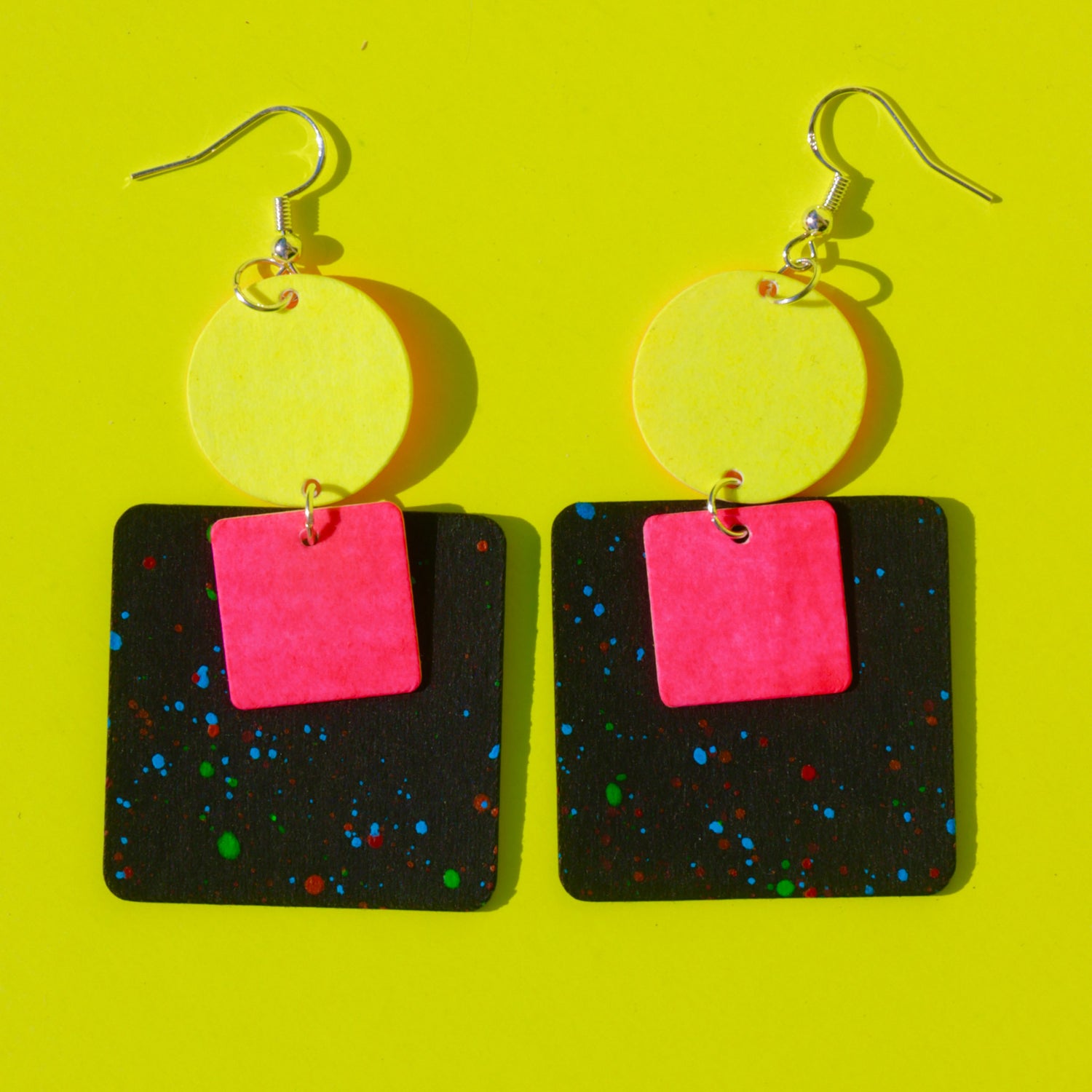 Vegane Ohrringe in Kreis- und Rechteckform in Pink und Gelb auf gelbem Hintergrund – Schmuckworkshop nachhaltig.