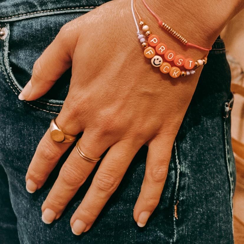 Hand hält zwei Perlenarmbänder in Korallfarben, DIY Schmuckworkshop bei Grimms Garten Berlin