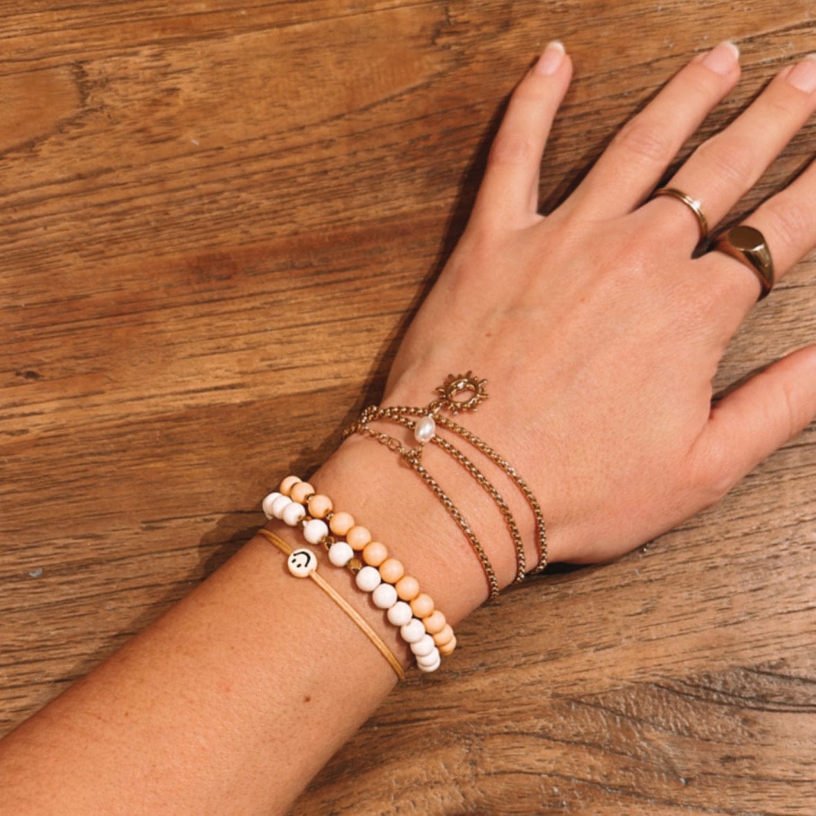 Arm trägt verschiedene Perlenarmbänder in Weiß und Gold, DIY Schmuckworkshop bei Grimms Garten Berlin