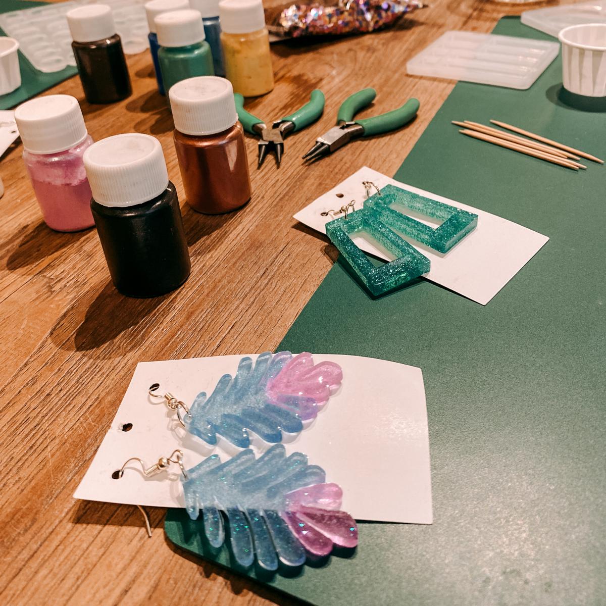 Zwei fertige Resin Ohrringe mit Glitzer und Blumen auf Tisch – DIY Epoxidharz Schmuckkurs in Berlin.