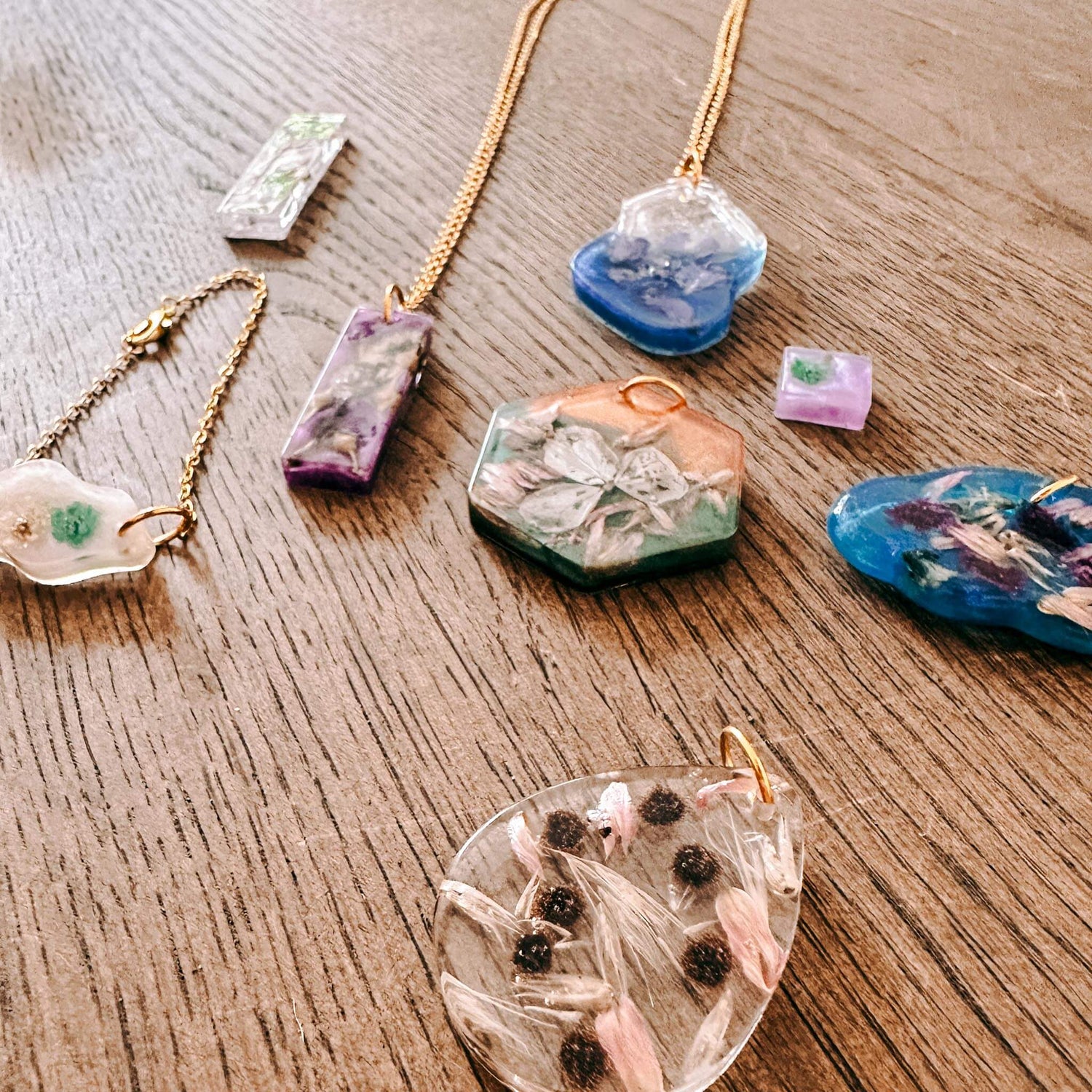 Viele verschiedene Resin-Anhänger mit Trockenblumen auf Tisch – resin jewelry, diy schmuck, auch für Firmenevents