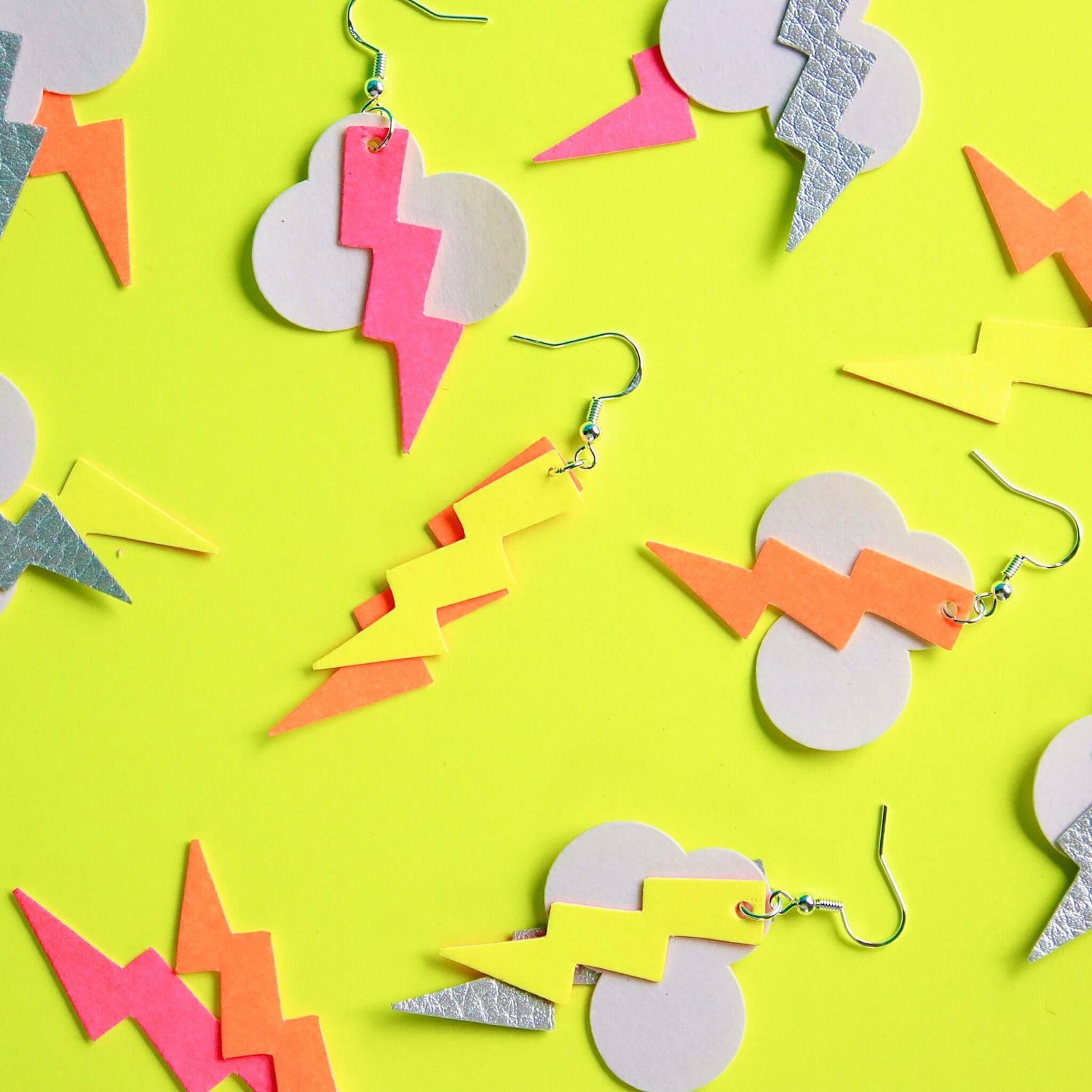 Neon-gelber Hintergrund mit bunten Blitz-Ohrringen aus veganem Leder – DIY Schmuckworkshop.