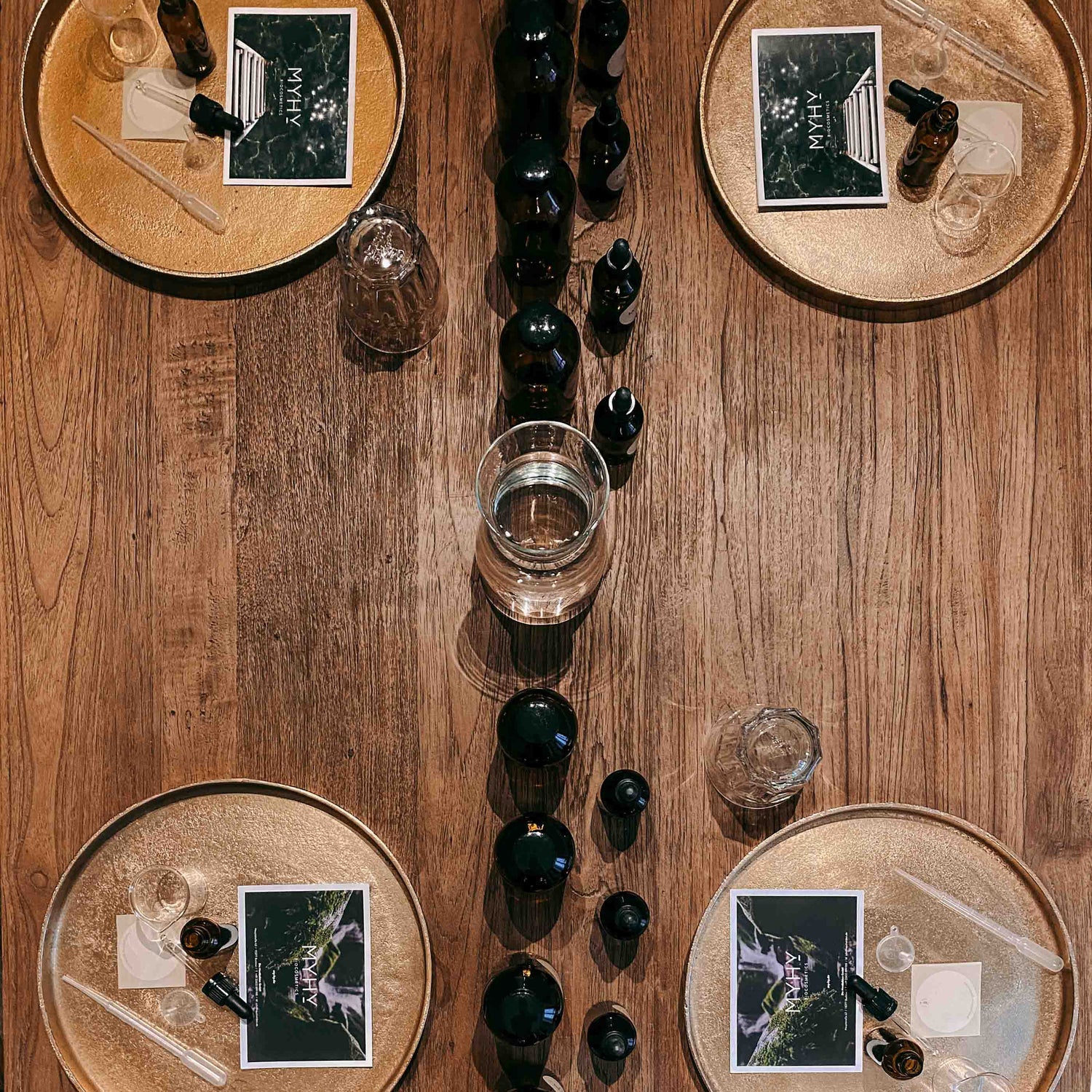 Tisch mit vier goldenen Tabletts und vielen kleinen Flaschen – bio facial serum workshop, naturkosmetik diy, ätherische öle.