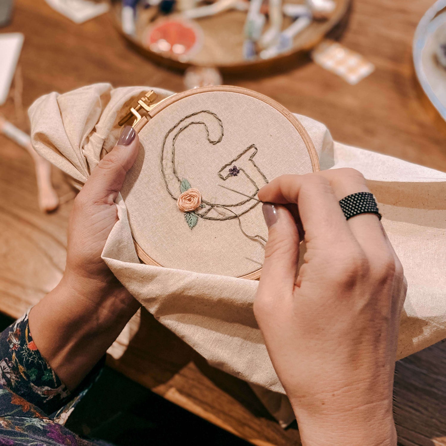 Zwei Hände sticken Buchstaben mit Nadel auf Stoff – Stickkurs, Handstickerei für Anfänger