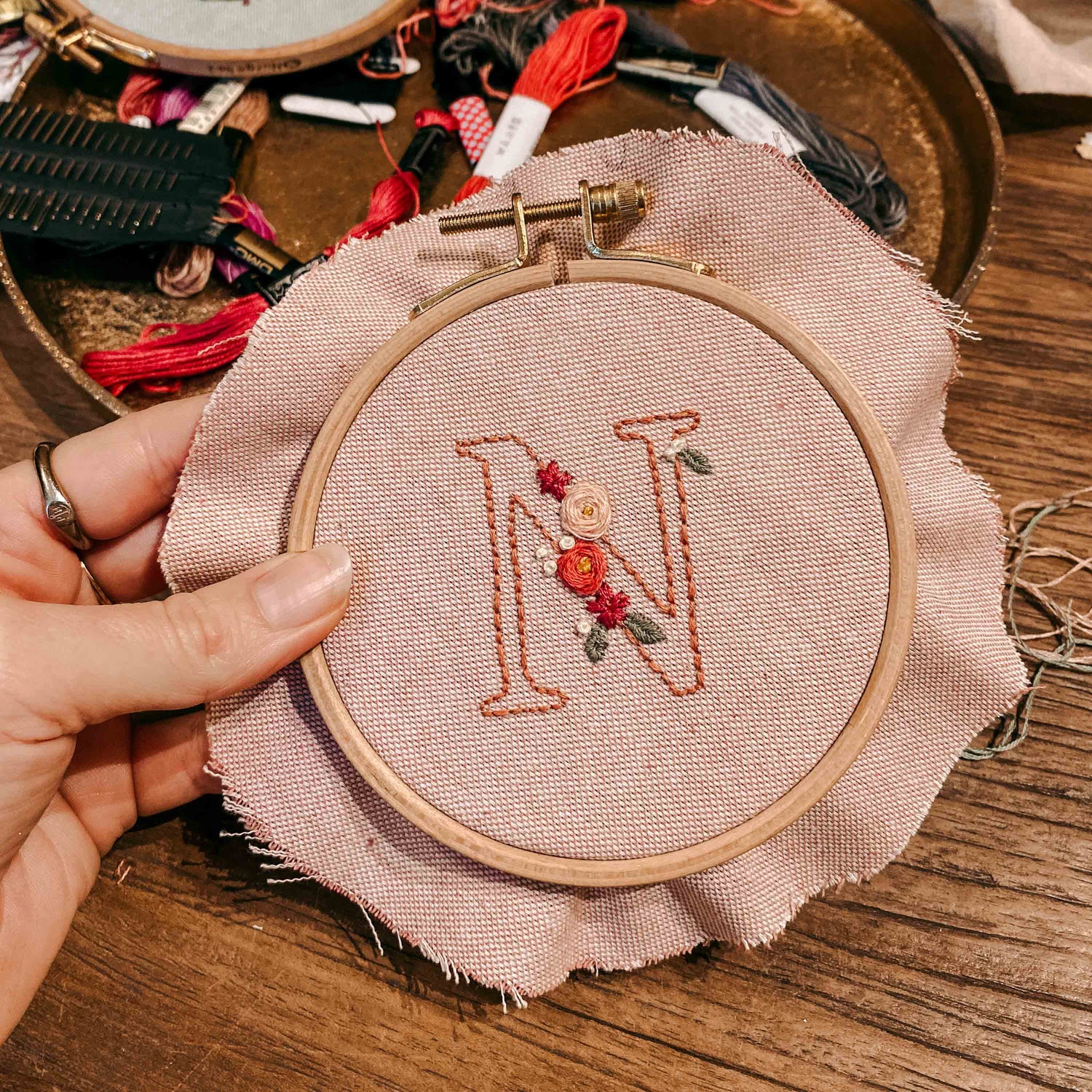 Hand hält gesticktes Monogramm N mit Blumen – DIY Stickkurs, individuelle Stickerei Workshop