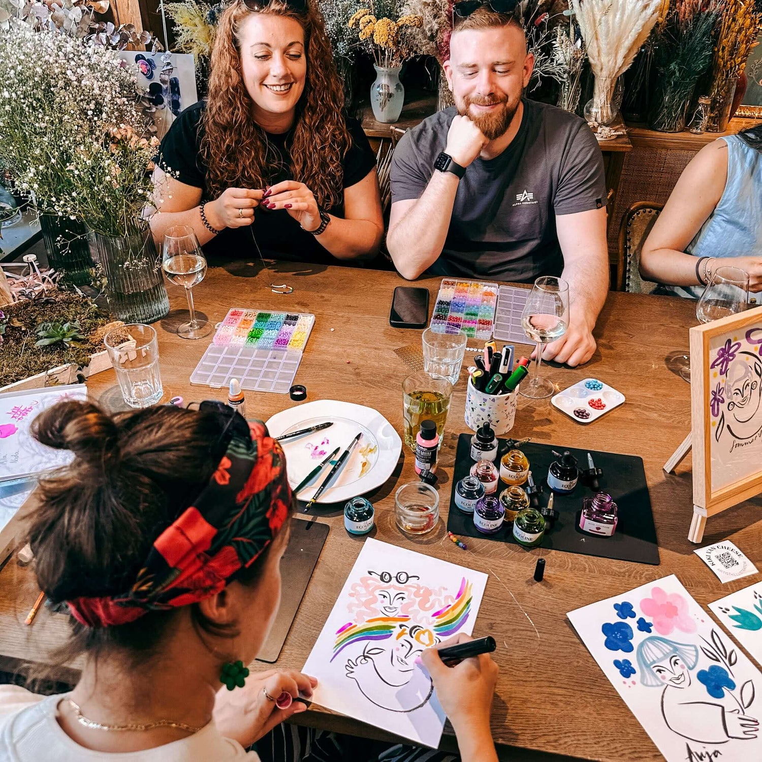 Mehrere Personen malen Portraits am Tisch mit Materialien – Team-Event, Firmenevent oder Kundenaktion.