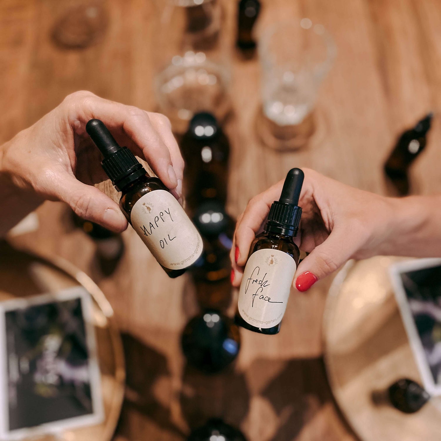 Zwei Hände halten Flaschen mit Aufschriften „Happy Oil“ und „Fresh Face“ – bio facial serum, naturkosmetik workshop, diy hautpflege.